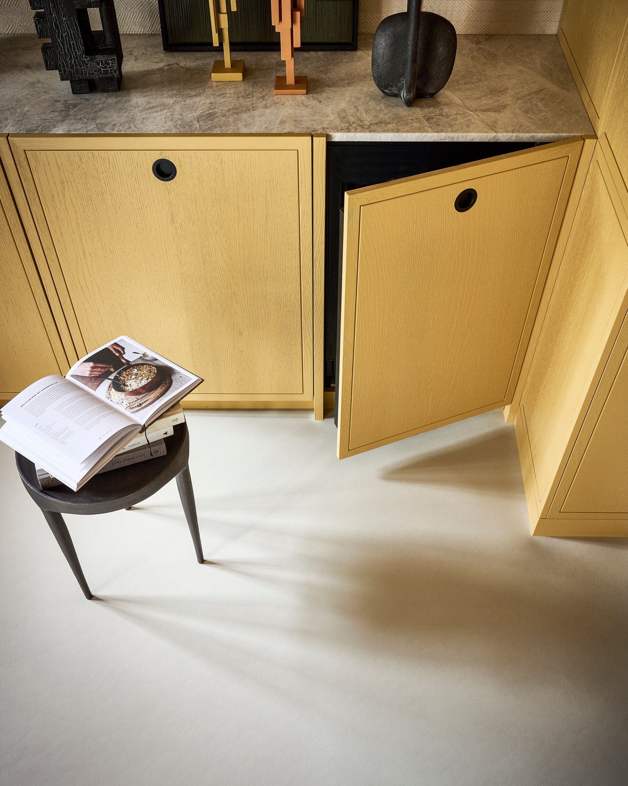 Marmoleumvloer in Truffle Basic, 200 cm breed, per m² € 50,40.M.m.v. hkliving.com (oranje en gele sculpturen Skyline), zarahome.com (gele borden, zwarte vaas), fermliving.com (zwarte organische vazen), 101cph.com (zwarte schaal op pootjes), edithbeurskens.com (zwarte sculptuur Odile), vtwonen.nl/shop (glazen etagère Damo van Ferm Living), art-lines.nl (kunstwerk No. IV in Moss Green). Overig privébezit. vtwonen 04-2024 | productie Tanja Saarberg | styling kim van rossenberg | fotografie sjoerd eickmans