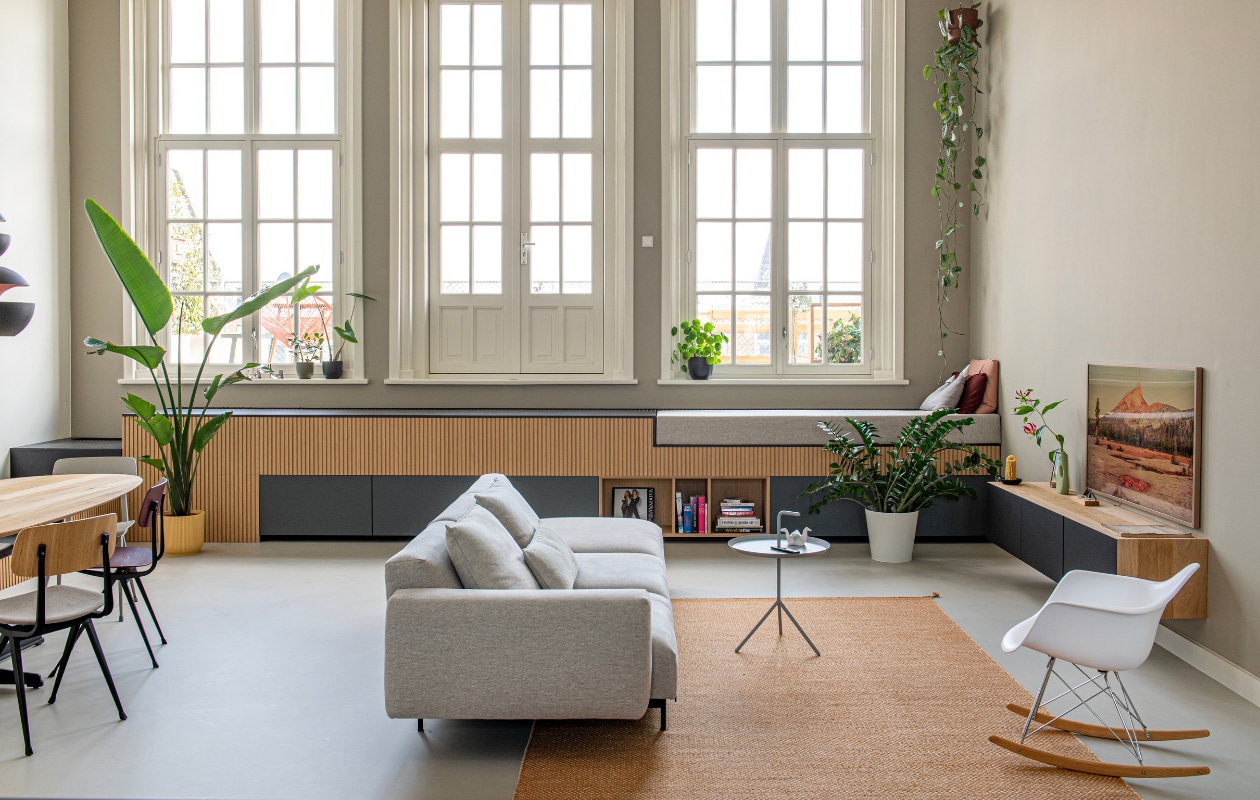 Eetkamerstoelen Revolt en bijzettafel DLM van Hay. Eettafel, kast onder de ramen en tv-meubel op maat gemaakt door Houtmerk. Bank en vloerkleed Muuto, schommelstoel Eames Rar van Vitra, plantenpotten van gerecycled plastic Elho, flesvaas Foekje Fleur, televisie The Frame van Samsung. Roze en rood kussen Muuto, kussen in de vorm van een berg op daybed gemaakt door Ingrids moeder. Overig onbekend. vtwonen special binnenkijken 11-2023 | productie De Binnenkijkers | styling Jeske Weel | fotografie Caroline Coehorst