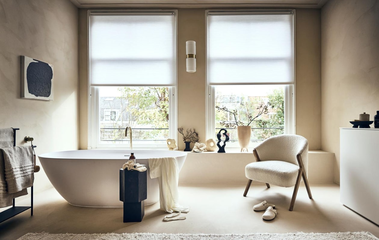 Witte stoel met houten poten en badstof bekleding € 299,-, badmat op rek € 19,99, handcrème € 15,99, vloerkleed € 219,-, sloffen € 25,99, beige bakje met deksel € 17,99, ochtendjas € 69,99, scrubhandschoen op zwart kastje, prijs op aanvraag (zarahome.com). Zwart rek van Ferm Living € 189,- (vtwonen.nl). Beige plaid € 99,-, vaasje met rond gat links € 54,95, beige vaas in het midden € 57,95, zwarte siervorm € 79,95, grote beige vaas € 89,95, borstel € 15,95 (eijerkamp.nl). Kunstwerk aan wand, prijs op aanvraag (@ansdekruyf). Papieren kunstwerk € 150,- (elsavisser.com). Zeep in fles € 18,-, losse zeep € 22,-, zeepfles op zwarte kruk, prijs op aanvraag (sukha.nl). Zwarte natuurvorm € 35,- (taxidermy.nl). Zwarte schaal op drie poten € 19,99 (hm.com). Zwarte kruk € 249,-(aedamanthony.nl). Muurverf onbekend. Overig privébezit. vtwonen 01-2023 | styling liza wassenaar | fotografie sjoerd eickmans