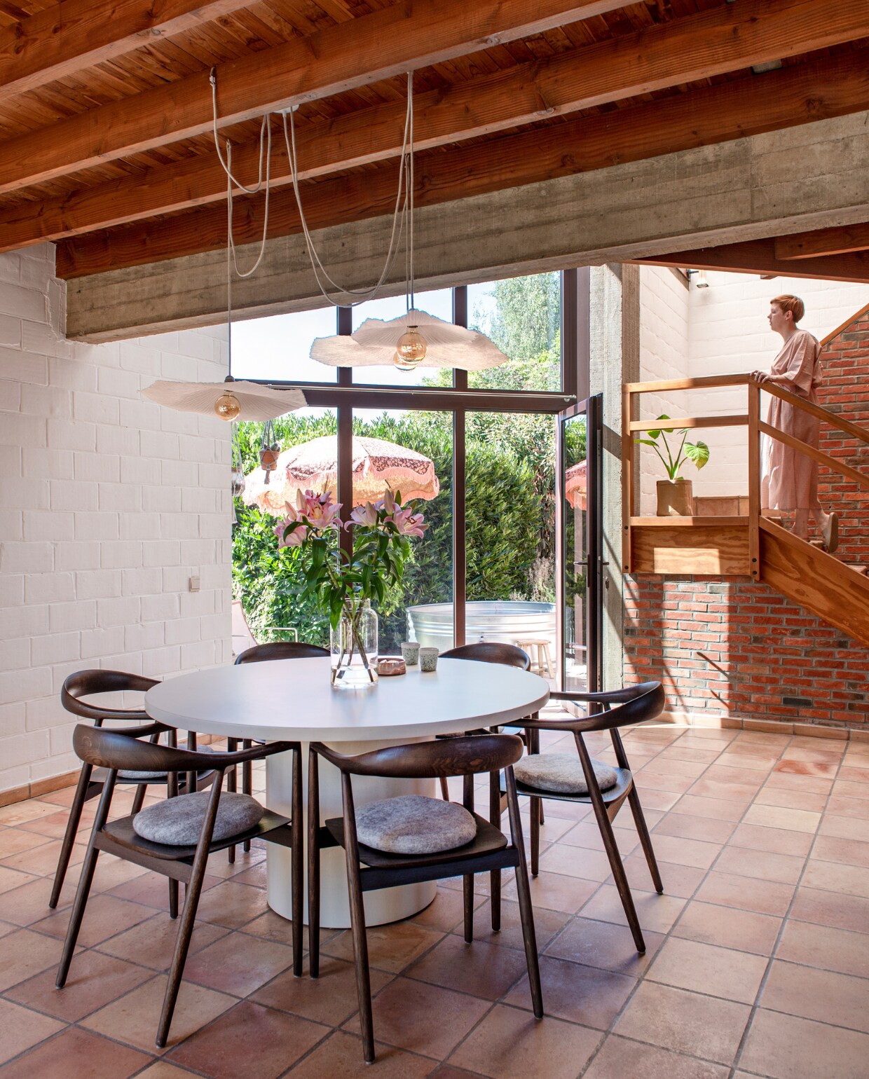 Tafel ByMi Interior Design. Stoelen Dipe Concept Interior. Hanglampen Swapp. Kussens op stoelen Hay. Vaas Bloomon. Servies Sara Delesie Keramiek en HKliving. Parasol HKliving. Bloempot onbekend. vtwonen 03-2023 | productie De Binnenkijkers | styling Jeske Weel | fotografie Caroline Coehorst