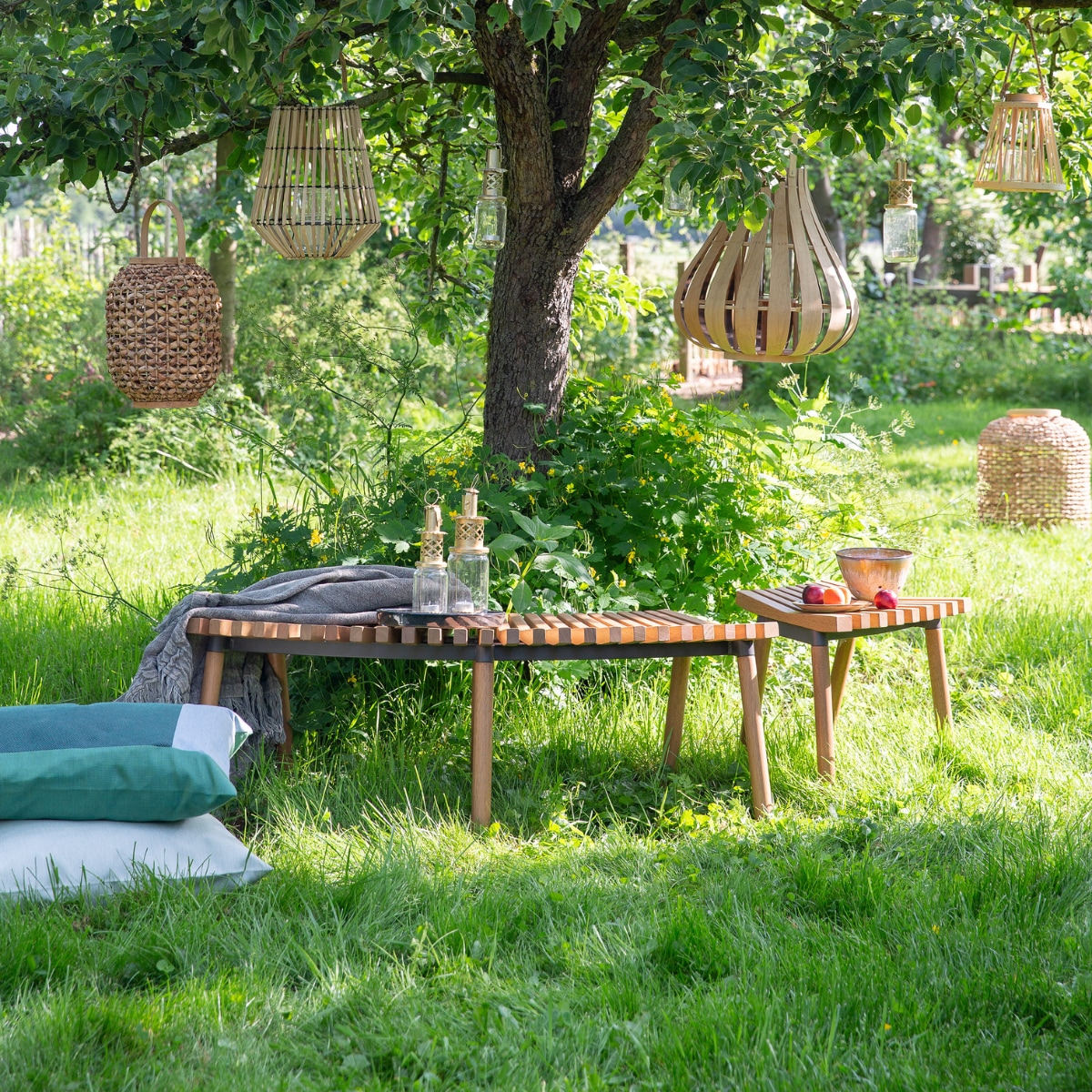 Rond bank Överallt, 124x49x44 cm (bxdxh) € 119,-, kruk Överallt € 49,95 (ikea.nl). Lantaarns van links naar rechts in de boom: XL van gevlochten gras en jute € 48,25 (deens.nl), van bamboe € 4,95 (action.com), jampot maat M € 19,95 (householdhardware.nl), van bamboe met glas erin van Pols Potten, 45x48 cm € 99,- (vtwonen.nl), jampot maat M € 19,95 (householdhardware.nl), taps toelopend van bamboe met glas erin € 7,95 (action.com). Lantaarn XXL van gevlochten gras en jute € 110,25 (deens.nl). Mintgroen duurzaam buitenkussen Solid, 60x60 cm € 110,-, mintgroen buitenkussen Bengali € 95,- (kus-sen.nl). Linnen plaid,130x170 cm € 125,- (aaimadewithlove.com). Lantaarns van gerecyclede jampotten vanaf € 15,95 (householdhardware.nl). Fruitschaal en schotel € 52,- (lilokeramiek.nl). vtwonen 08-2019 | styling Leonie Mooren | fotografie Anouk de Kleermaeker