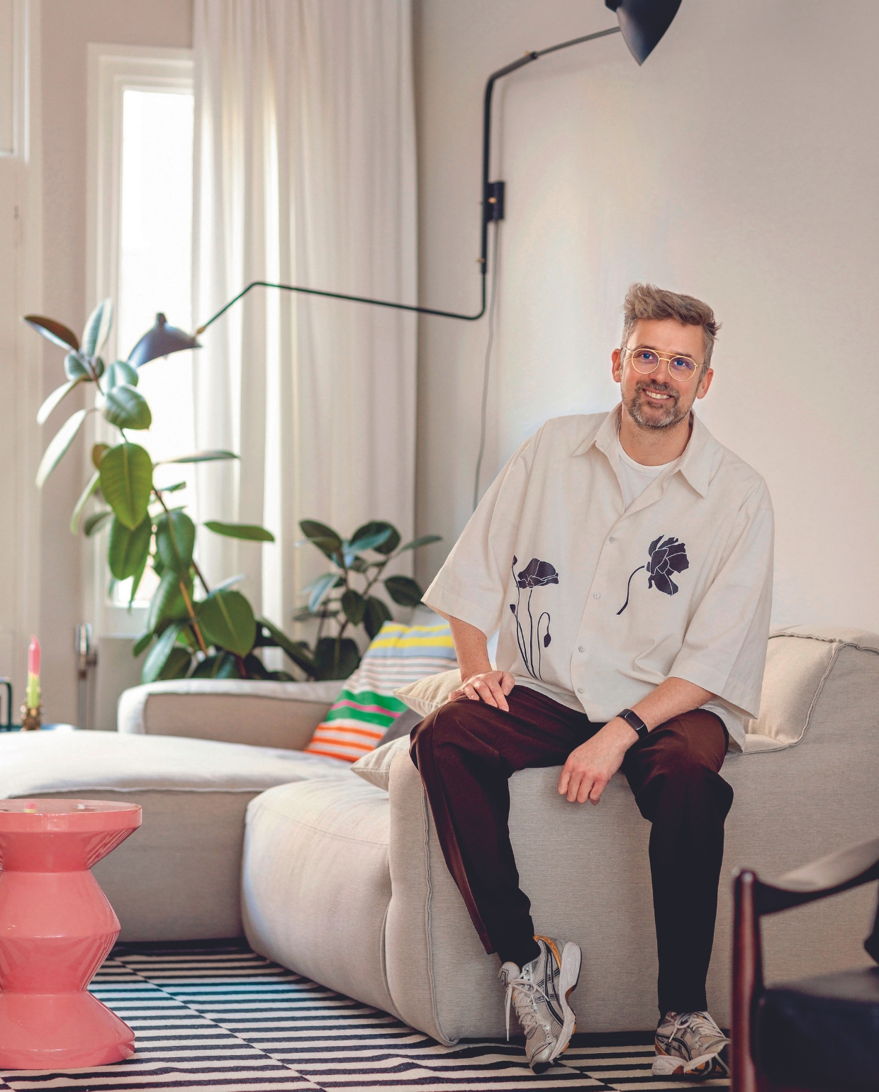 Patrick is zielsgelukkig met deze bank van Fést, waar hij zichzelf op trakteerde na de verbouwing. Kleed Ikea, bijzettafel Polspotten, wand-lamp Serge Mouille. vtwonen 03-2024 | fotografie Ernie Enkelaar