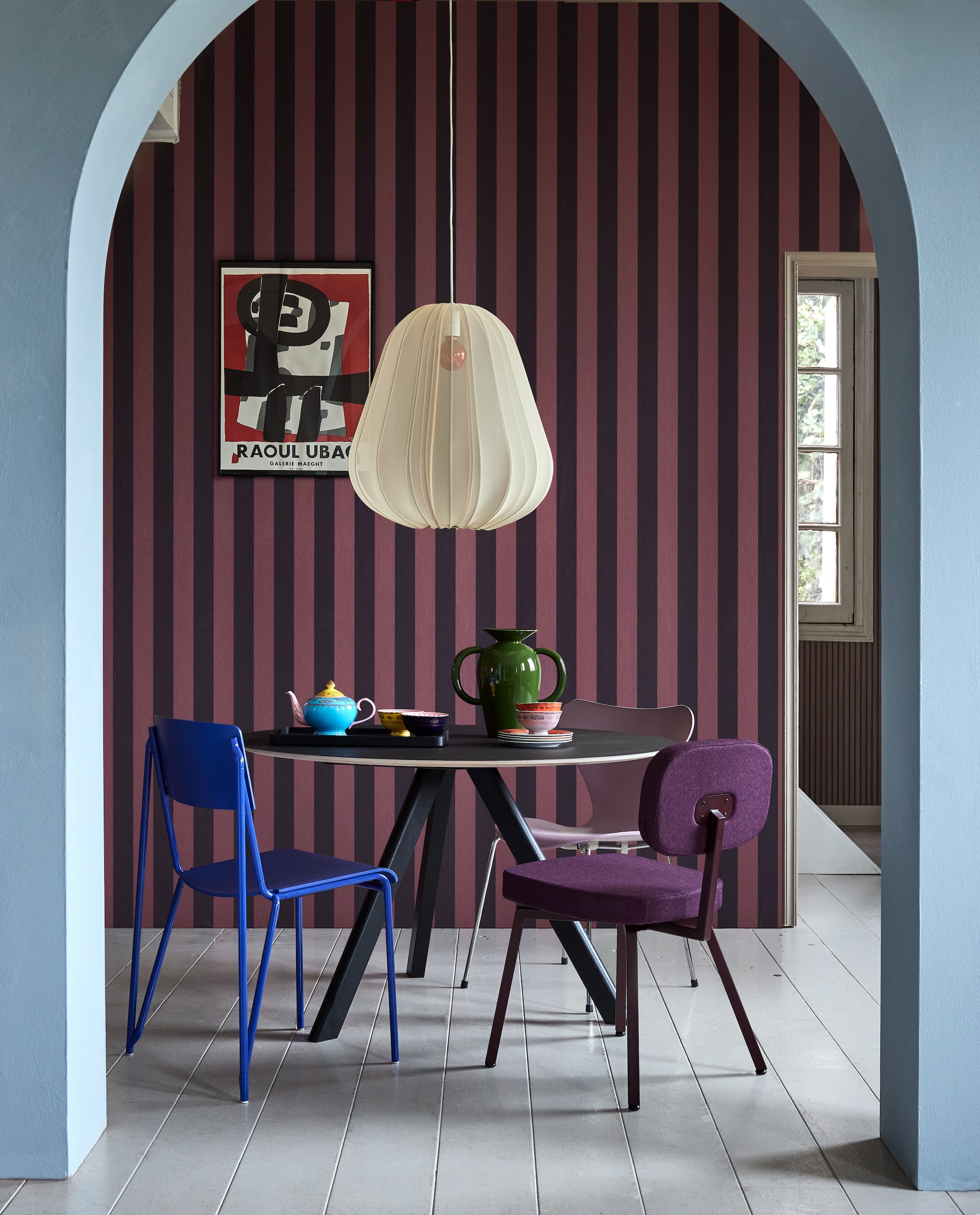Muurverf Jackie Blue van Lab Paint (vestingh.nl). Behang Othello Cyprian Sassafras, 0,53x10 m (bxl) (masureel.com). Eettafel CPH20, eikenhout met linoleum blad, 120x74 cm (xh), blauwe eetkamerstoel Petit, aluminium en eikenfineer (hay.nl). Stoffen hanglamp Balloon van Bolia, 53,5x60 cm (xh) (vtwonen.nl/shop). Lichtpaarse vlinderstoel van Arne Jacobsen, metaal en eikenfineer, auberginekleurige stoel MK van De Machinekamer, staal en stof (demachinekamer.nl). Porseleinen theepot Grandpa, porseleinen kommen Grandpa, porseleinen borden Grandpa (polspotten.com). Keramieken vaas Momento van &Tradition (groenenakker.nl). Overig privbezit.  vtwonen 04-2024 | styling Fietje Bruijn | fotografie Alexander van Berge