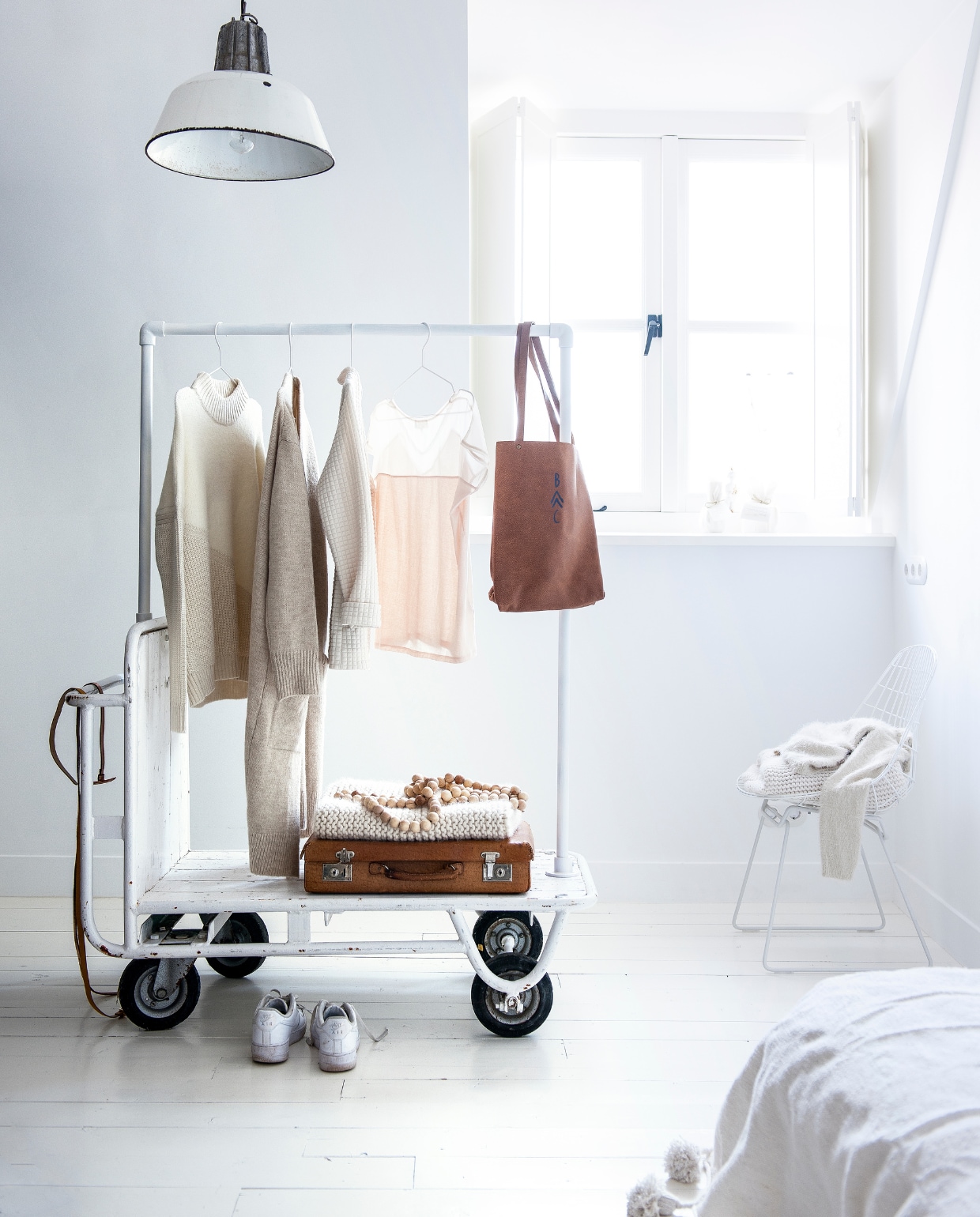 Hanglamp € 125,- (Spoor 38). Houten kralenketting € 39,-, kleding op stoel vanaf € 79,95, kaarsen op vensterbank vanaf € 15,95 (It’s Loft). Koffer € 29,95 (Loods 5). Witte draadstoel van Cees Braakman € 395,- (Pastoe). Witte deken met pompons van Kiss &amp; Play € 175,- (LisLoves). Kleding v.l.n.r. off-white trui € 89,99, ecru vest € 79,99, off-white jasje € 79,99, roze T-shirt € 74,95 (Sissy-Boy). Leren tas van Bobo Choses € 150,- (Orange Mayonnaise). Gebreide deken, riemen en schoenen privébezit. vtwonen 13-2015 | Styling Kim van Rossenberg | Fotografie Sjoerd Eickmans