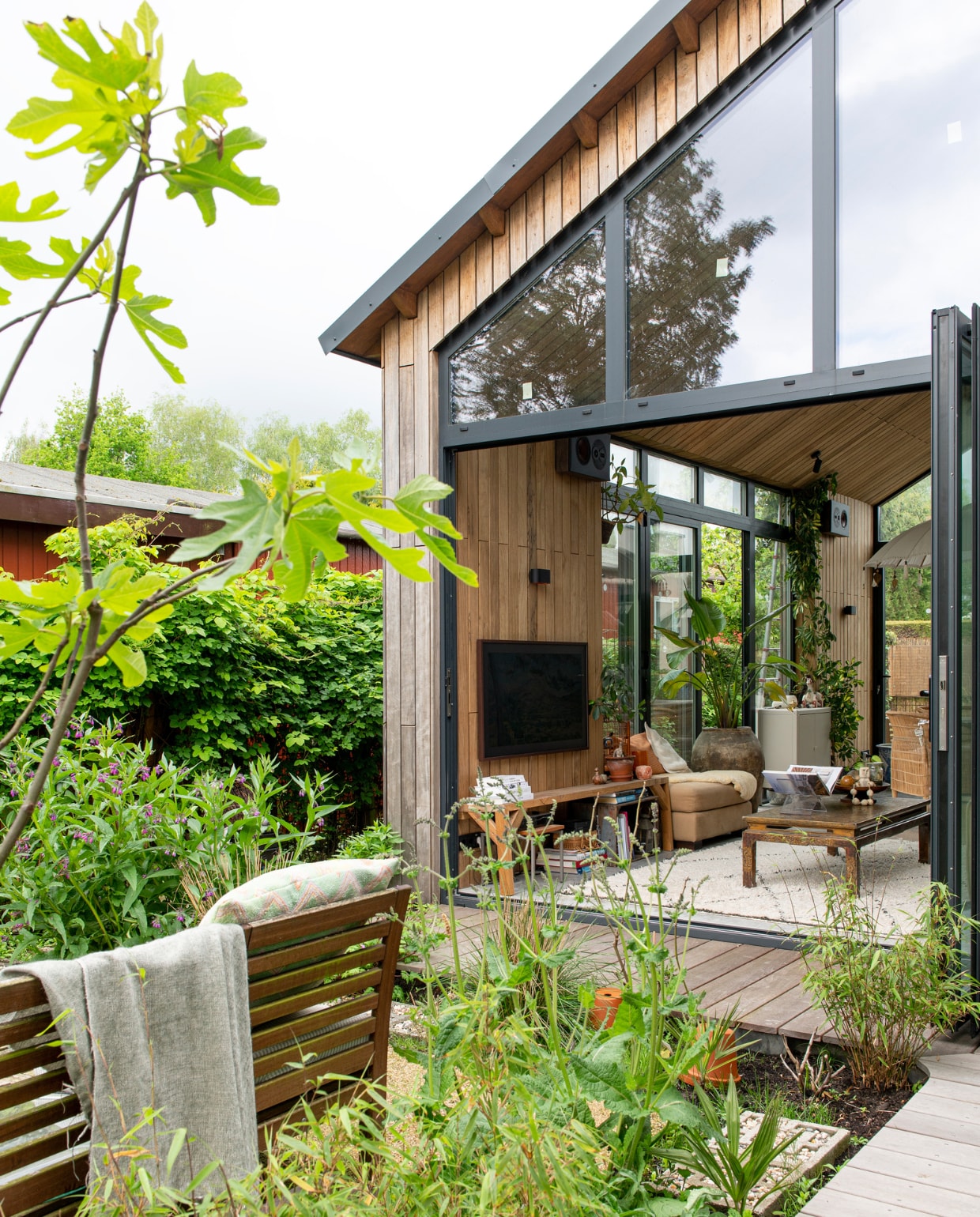 Gevel met hout Fraké van Platowood, biologische eetbare planten Sprinklr, aarde Bio-Kultura, kooi meegenomen uit China, parasol meegenomen uit Indonesië, lampen veilingsite, speakers Bluesound. Poef, salontafel, pot en vloerkleed tweedehands. Houten bank binnen zelfgemaakt, tv Samsung. Overig onbekend. vtwonen DIY special 08 | fotografie Caroline Coehorst