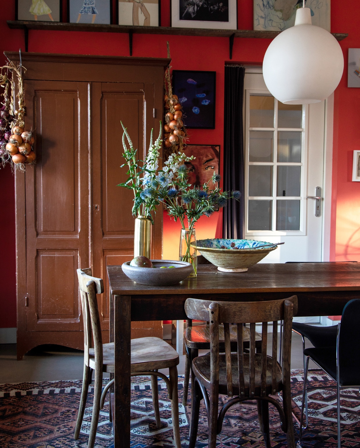 Tafel Jan van IJken, caféstoelen Burbri, stoel rechts 40/4 van David Rowland via Tim Tom, hanglamp Satellite van Vilhelm Wohlert via De Vreugde Design, kast vintagemarkt, schaal links vintage, schaal rechts Polspotten, metalen vaas Zara Home, glazen vaas Loods 5, vloerkleed Kilim. Kunst: op plank Piet Paris, midden Louise te Poele voor Claudia Sträter, rechts Hans Schabracq, tussen kast en deur boven Louisiana van Onna, onder Anthony Cudahy. Muurverf Shocking Coral, houtverf Quiet Blush, beide Lab Paint van Vestingh.