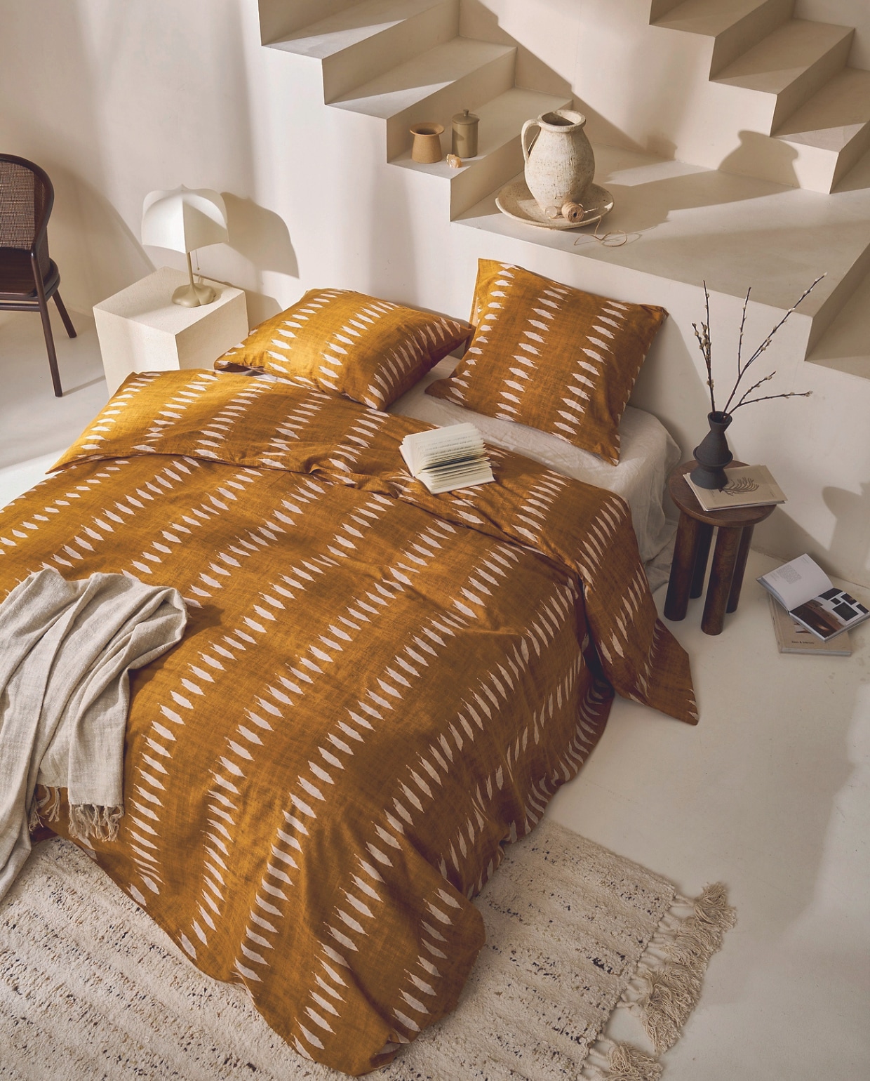 Katoenen dekbedovertrek Ikat in okergeel, 140x200/220 cm € 49,95, 200x200/220 cm € 89,95, 240x200/220 cm € 99,95 en 260x200/220 cm € 119,95. M.m.v. nordal.dk (bijzettafel van hout, vloerkleed en stoel), zarahome.com (kubus, vaas en schaal), vtwonen.nl/shop (lamp van Ferm Living). Overig privébezit. vtwonen 03-2024 | productie Tanja Saarberg | styling Cleo Scheulderman | fotografie Jeroen van der Spek | assistentie Aylin Citanak