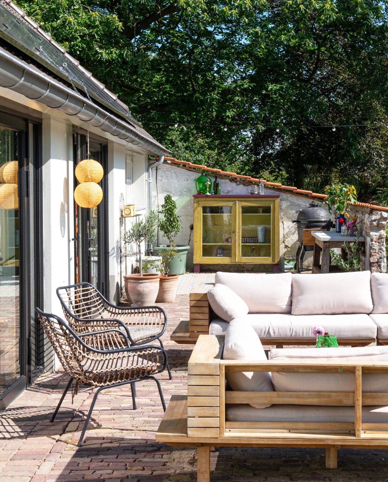 Loungeset Lissabon Naturel van Karwei, tuinstoelen Leen Bakker, lampions Action, plantenpotten onbekend. Kast achtergelaten door vorige bewoners, zelf geschilderd en pootjes gemaakt van betonblokken. Barbecue Grill Guru XL. vtwonen special 131-2024 | productie De Binnenkijkers | styling Jeske Weel | fotografie Caroline Coehorst