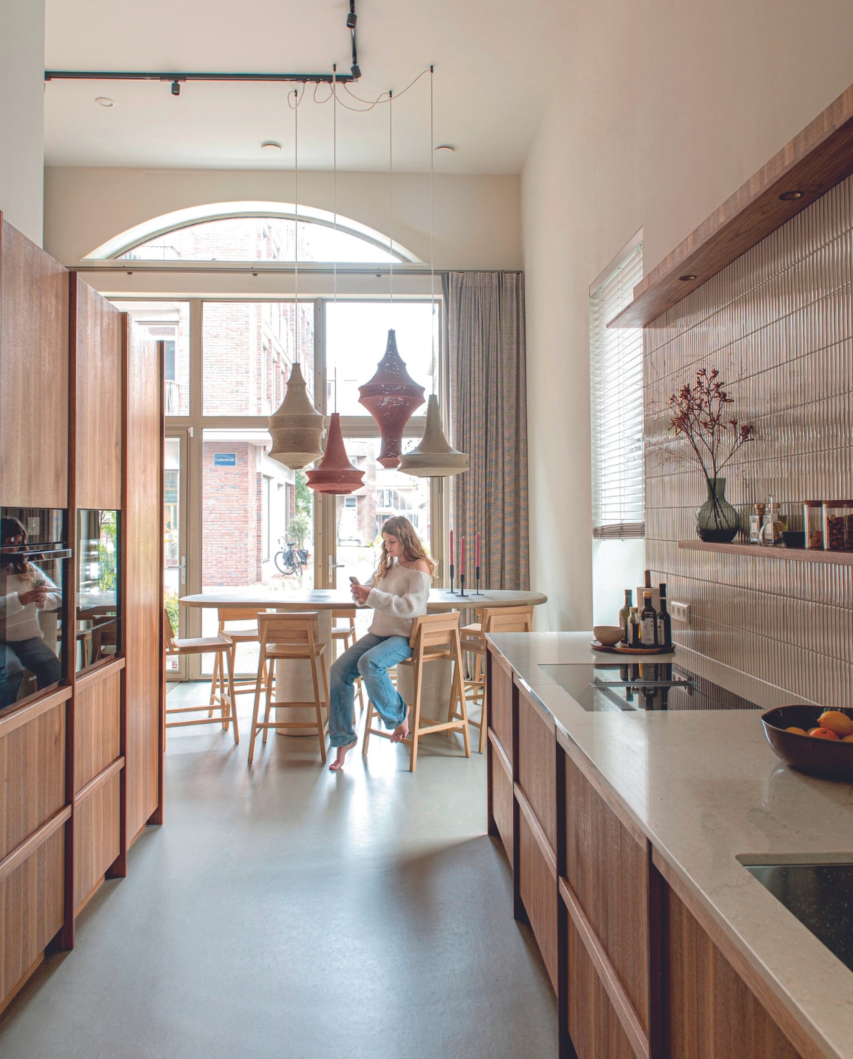 Keuken eigen ontwerp, uitgevoerd in Italiaans walnoot door Gebroeders De Wilde, wandtegels Kol Tegels &amp; Sanitair, apparatuur Siemens via Andrea XL, handgemaakte hanglampen Hamimi, tafel Arredoo, krukken N3 van Ethnicraft via ByDennis, houten plateau Dille &amp; Kamille, muurverf Shaded White van Farrow &amp; Ball, vloer vtwonen 016 Kwarts van Marmoleum. Overig onbekend. vtwonen 03-2024 | productie De Binnenkijkers | styling Jeske Weel | fotografie Caroline Coehorst