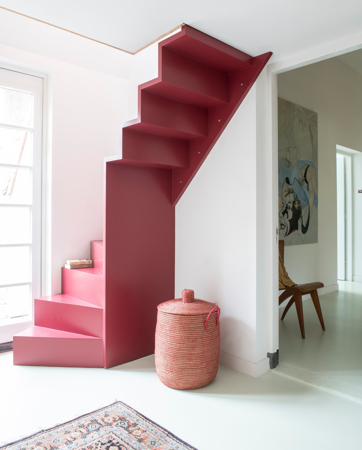 Eyecatcher in huis is zonder meer de trap, ontworpen door Clementine’s vriend Andrew March, met zijdeglans acrylverf 96 Radicchio van Farrow &amp; Ball. Wasmand, stoel en vloerkleed cadeau gekregen. Schilderij ‘Cowboy’ van Stella de Boo. Vloer ComfortFloor Pro van Sika in kleur S1010/GY05. vtwonen special 03-2020 | productie InsideHomePage | styling Kristel de Jong | fotografie Louis Lemaire