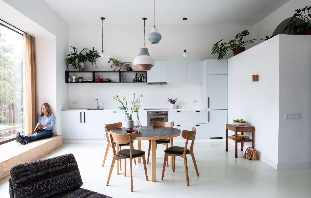 Keukenkasten Kvik. Fronten gemaakt door de aannemer, blad Hi-Macs. Kleur blauw Pale Powder van Farrow &amp; Ball. Zwarte grepen Ikea. Tafel van Artek. Stoelen Ami van Rowico. Erboven Cirque hanglampen van Louis Poulsen. Blauw-roze vaas is een cadeau. Glazen vaas rommelmarkt.Stof gordijnen Jules Sienna van The Alfred Collection. Los element van vintage Artifort bank. Keuken: hanglampen Decovry. Zwart vaasje cadeau gekregen. Het houten art deco tafeltje kreeg Clementine van haar moeder toen ze net op kamers was, het kunstwerk erboven is van Alf Slegers. Fruitschaal van een brocante. vtwonen special 03-2020  | productie InsideHomePage | styling Kristel de Jong | fotografie Louis Lemaire