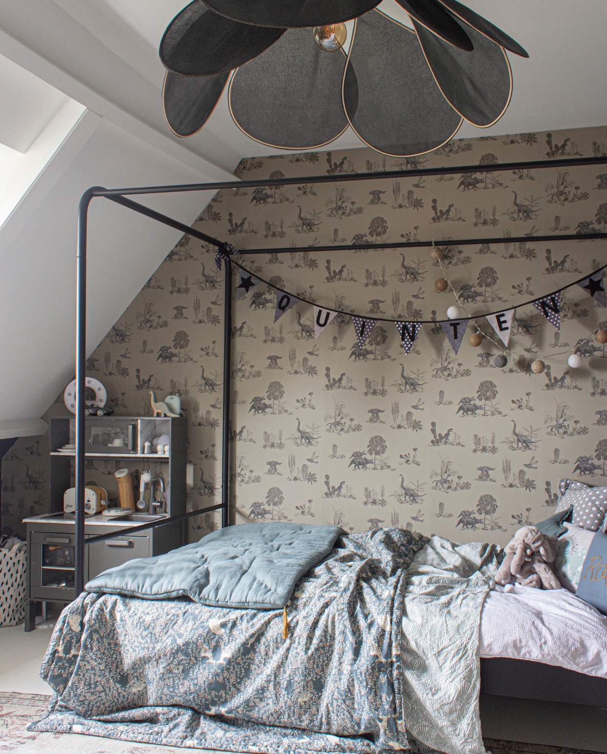 Quintens kamer met hemelbed Bunk van vtwonen. Bloembladlamp Georges Store via Archive Store. Behang Sian Zeng via Lidor. Gebloemde deken Garbo &amp; Friends, matras erop Numero 74. De speelkeuken van Ikea heeft Angela zelf antraciet geverfd en beplakt met marmerfolie. Vloerkleed Rozenkelim. vtwonen special 03-2020 | styling Angela Zonneveld, Decorush | fotografie Anne Kohnke