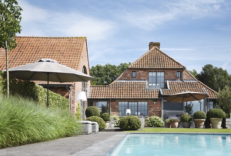 Deze tuin ligt in een regio die nogal gevoelig is voor wind. De halfhoge hagen van beuk zorgen er echter voor dat het ’s zomers toch aangenaam vertoeven is in het zwembad. Veronique De Walsche