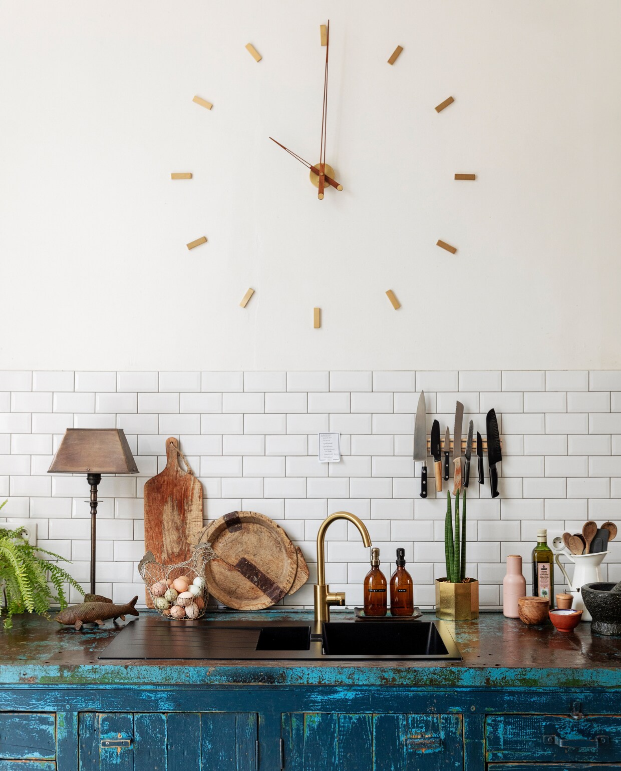 Muurverf Ral 9010. Metrotegels Impermo, klok Nomon. Keuken/oude schroefbank en tafellamp Woontheater. Planken houtzagerij, lepelpot Ikea. Eiermand en snijplanken brocante. Overig onbekend. vtwonen 10-2023 | styling Ilona Jongepier | fotografie Dana van Leeuwen