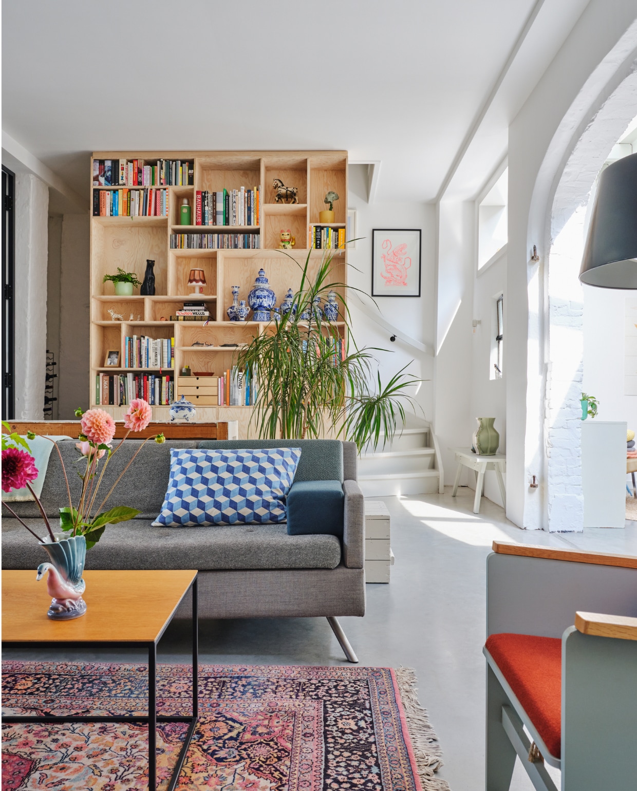 Bank Lot Studio Parade via Vrienden. Geometrisch kussen OXO. Salontafel eigen ontwerp. Fauteuil Katrijn van Floris Hovers via Vrienden. Vloerkleed vintage. Kastenwand op maat gemaakt van Pools grenenhout. Ingelijste prent Trobbies. Wit bankje Piet Hein Eek met daarop de Carter Vase van Floris Hovers via Cor Unum. Overig onbekend. vtwonen special binnenkijken 2022-131 | fotografie Rene van der Hulst | styling Marloes Wolfs | tekst Caroline Hülsenbeck