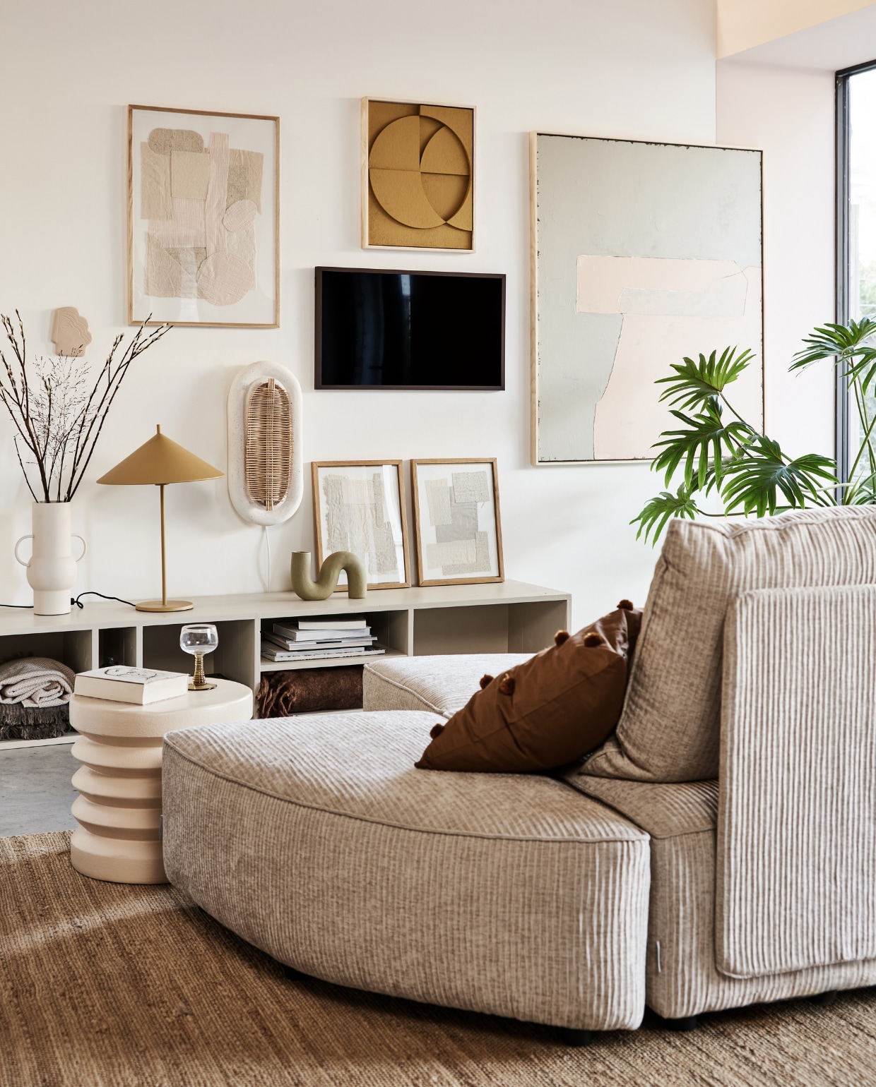 Televisie The Frame, 32 inch € 429,-, verwisselbare walnoothouten lijst The Frame € 129,- (samsung.nl). Kast in kleur Skimming Stone 241 van Farrow &amp; Ball, prijs op aanvraag (combitex.nl). Handgemaakte ovale wandlamp Aplique Ovalado € 299,-(lanena-home.com). Sofa Hunter uit diverse losse onderdelen: poef € 419,-, element met rug € 1009,-, element zonder rug € 419,- (zuiver.nl). Bruin kussen met pompons van Ferm Living € 29,95,-, roze stoneware bijzettafel van HKliving € 159,- (vtwonen.nl). Vaas Twisted in mat olijfgroen € 34,95, hennep vloerkleed 180x280 cm € 395,-, olijf/roze-kleurig abstract kunstwerk (rechts) 100x120 cm (bxh) € 549,-, okergeel kunstwerk boven tv van 43x4x53 cm (bxdxh) € 329,-, taupekleurig wandornament Face€ 37,95, crèmekleurige bijzettafel, 38x36 cm (Øxh), prijs op aanvraag, wijnglas met groene voet € 9,95, okergele lamp Triangel € 149,-(hkliving.nl). Stoffen kunstwerk in eikenhouten lijst € 89,-, kunstwerken in lijst op kast, per stuk € 69,-(sur-atelier.nl). Bruine en beige katoenen plaids in dressoir 130x170 cm, per stuk € 45,99 (zarahome.com). Donkerbruine plaid rechts in dressoir, 130x170 cm (bxl) € 65,- (maisonnl.com). Overig privébezit. vtwonen 02-2022 | styling Esther Jostmeijer | fotografie Bart Brussee