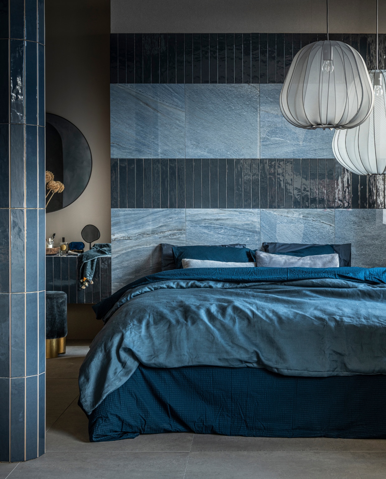 vtwonen collectie (Op de wand: vloer- en wandtegel Classic in kleur Heavenly Blue, glans, 60x60 cm, per m² € 77,95 (in mat € 71,90), wandtegel Marrakesh in kleur Ocean Blue, glans (ook in mat), 6,5x40 cm, per m² € 62,35. Op de vloer: vloertegel Raw in kleur Grey, 80x80 cm, per m² € 65,-). M.m.v. vtwonen.nl (stoffen hanglampen van Bolia), zarahome.com (ronde spiegel, staande spiegel, handdoek, donkerblauw beddengoed Minte van Essenza), ikea.nl (lichtblauw beddengoed Puderviva), melchiorinterieur.nl (poef, kussens), suhka.nl (houten schaal). vtwonen 11-2021 | productie Tanja Saarberg | styling Kim van Rossenberg | fotografie Sjoerd Eickmans