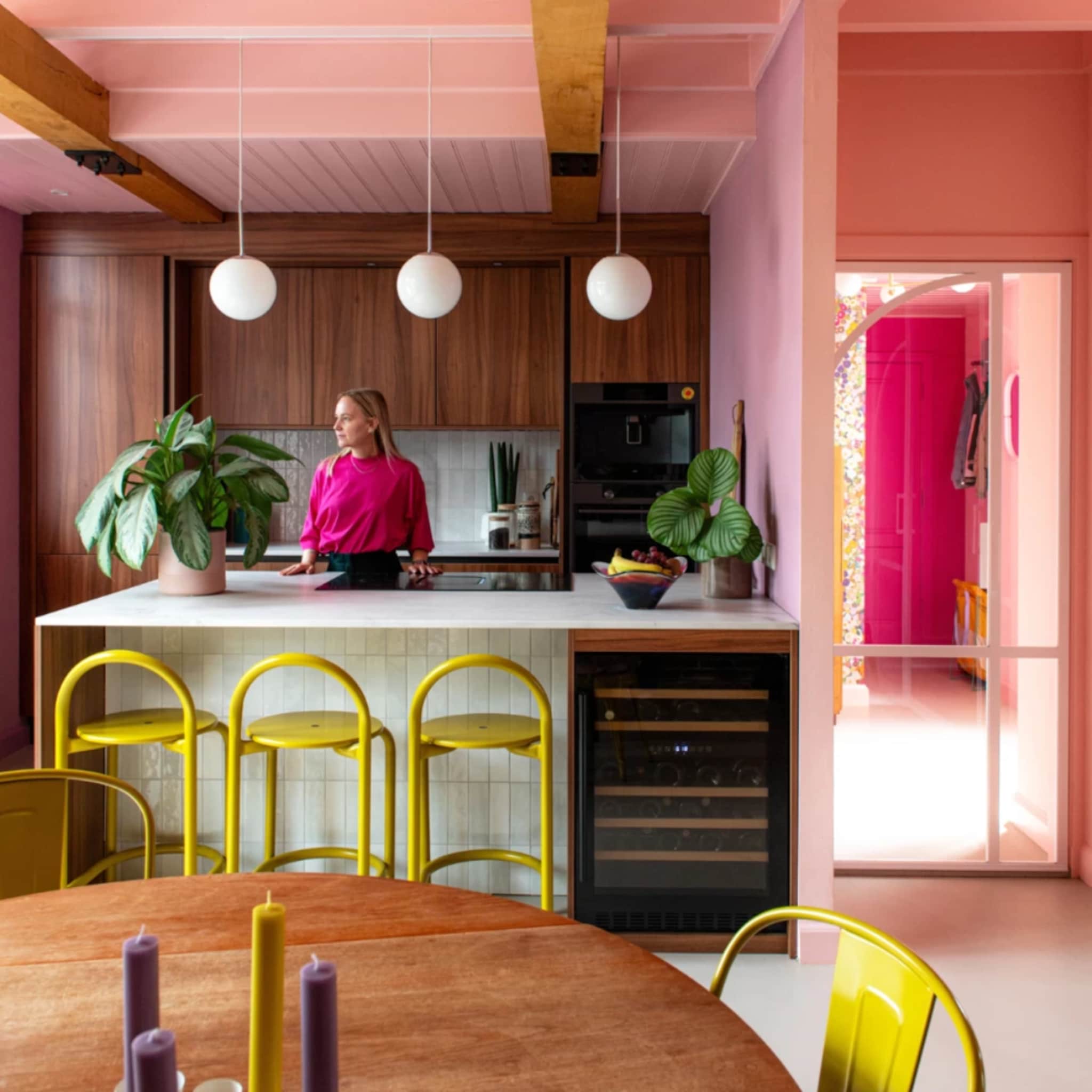 kleurijke keuken met gele barkrukken en roze wanden