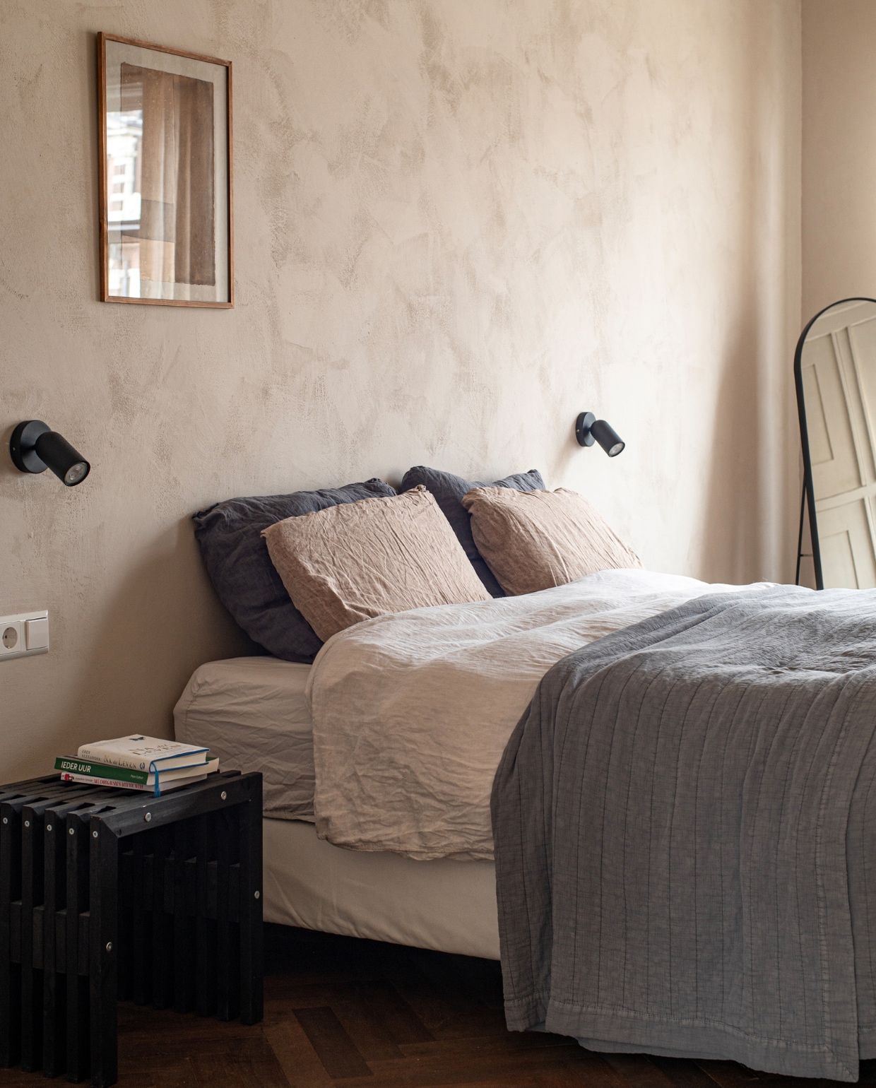 Sprei en nachtkastje Zara Home, bruine kussens By Mölle, schilderij Moos Willemsen, spiegel Loods 5, lampen onbekend, muurverf Mallorca van We Are Wow Makers via JAS. vtwonen binnenkijken special 131-2024 | productie De Binnenkijkers | styling Jeske Weel | fotografie Caroline Coehorst