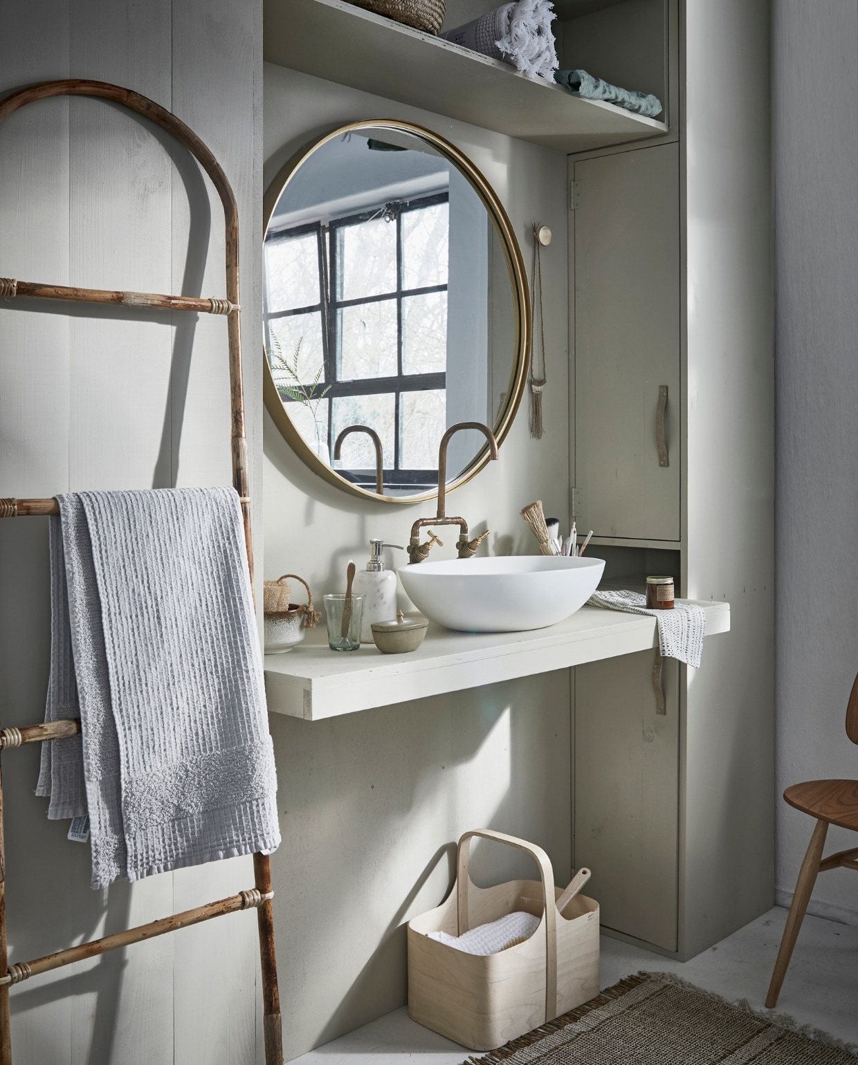 Grote ronde spiegel Ø 80 cm € 249,-, marmeren zeeppomp € 41,- (Nordal). Bamboe ladder € 54,05, vloerkleed 60x90 cm € 23,65 (Madam Stoltz). Witte wafeldoek € 49,95 (De Weldaad). Stoel Butterfly van Ercol € 625,- (De Machine- kamer). Berkenplex opbergmand 25x40x36 cm € 89,50 (Nordic New). Grijze handdoek 90x150 cm € 35,99(Zara Home). Waskom Girona, 57x40x15 cm € 381,- (Ton Scholten). Kraan € 75,- (Jan van IJken Oude Bouwmaterialen). Tadelakt zandkleurig potje met deksel € 19,95 (MaisonNL). Bureaulamp € 95,-(Vint. Amersfoort). Glas € 3,95, linnen doek in opbergzak € 75,-, witte opgerolde wafeldoek € 45,- (De Weldaad). Zandkleurig met bruine kom € 39,99, messing muurknop van Ferm Living € 20,-, geurkaars in bruin glazen potje € 16,- (Six and Sons). Rieten mand in kast vanaf € 9,99 (H&amp;M Home). Badborstel € 8,95 (Dille &amp; Kamille). De kast is geschilderd in de kleur Bone van Farrow &amp; Ball per 0,75 liter € 44,- (De Ru). De muur is geschilderd in de kleuren Egg White en Light Grey van vtwonen, per liter € 18,95, per 2,5 liter € 32,95 (Karwei). vtwonen 05-2018 | styling Cleo Scheulderman | fotografie Jeroen van der Spek