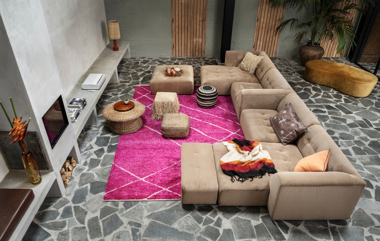 Ribfluwelen bank Vint van HKliving, element vanaf € 495,-, ronde poef met zwarte streep van Kave Home, 40x45 cm (hxØ) € 81,-, vierkante rotan poef van Kave Home, 50x50 cm € 87,-, mok met oor van Bloomingdale € 11,35, theekop met oor van HKliving € 10,30, oranje kussen van Hay € 75,-, poef Macaroni in geel velours van BePureHome, 42x162x80 cm (hxbxd) € 319,-(vtwonen.nl). Handgemaakt roze wollen vloerkleed, 260x360 cm € 2495,-, ronde rieten salontafel, 36x81 cm (hxØ) € 569,-, oranje glazen plaat € 150,-, lampenvoet € 139,-, lampenkap € 129,- (hkliving.nl). Poef met raffiafranje, 42x42x47 cm (hxbxd) € 129,-, bruin kussen met borduursel € 99,- (zenza.nl). Glazen vaas € 159,-, hoogpolig kussen € 119,- (fermliving.com). Gevlochten schaal € 39,-, bekers met terra glazuur € 7,50, wollen plaid € 395,- (householdhardware.nl). Theepot € 49,- (hay.dk). Beamer The Premiere van Samsung, vanaf € 2599,- (samsung.com). Pot en plant, prijs op aanvraag (dennisflowers.nl). vtwonen 02-2022 | styling Marianne Luning | fotografie Stan Koolen