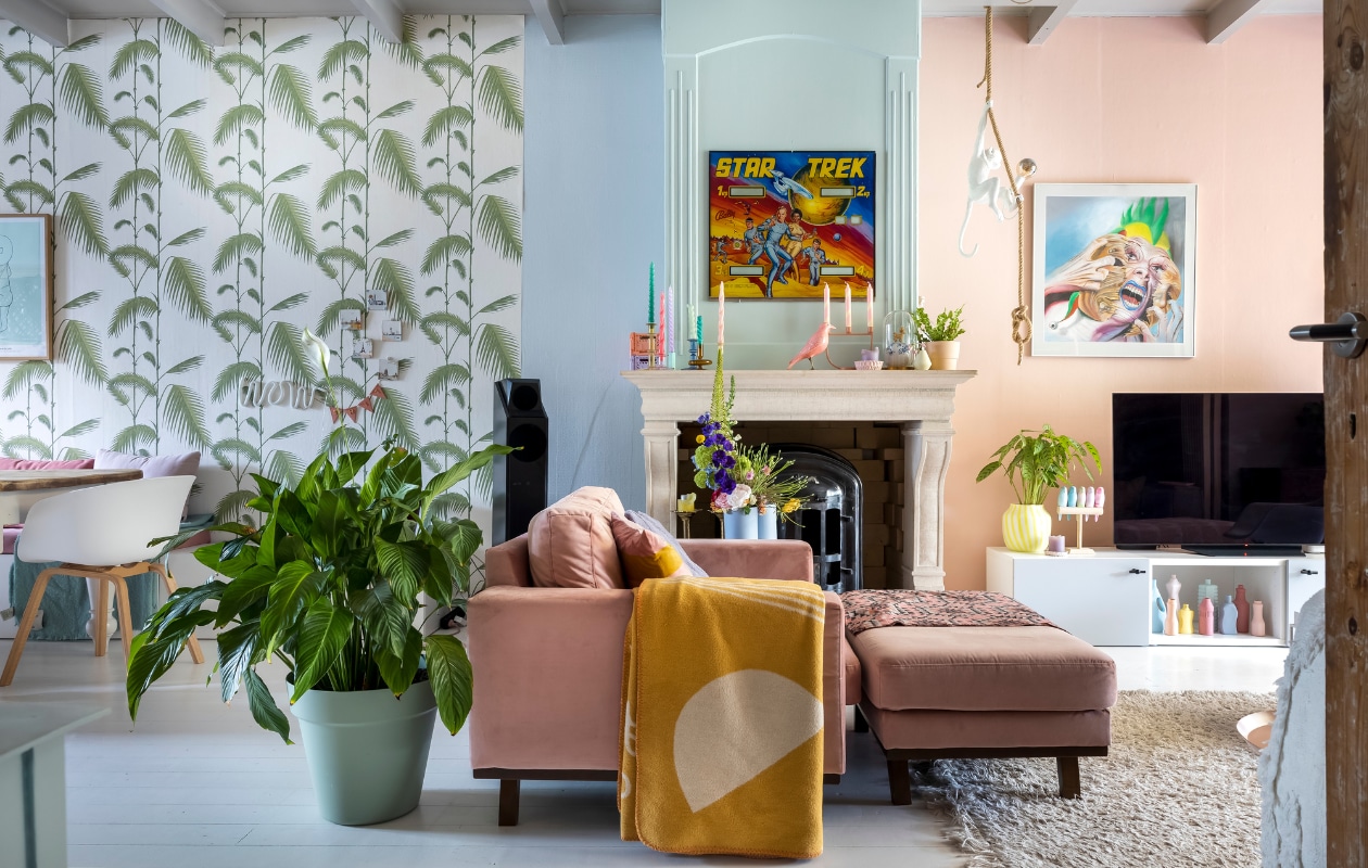 Roze stoel, hocker en vloerkleed Wehkamp. Gele vaas, kandelaars en kaarsen Hay. Roze kraai en gele deken Prchtg, vaasjes in de kast Foekje Fleur, parkieten Pete Cromer. Kast Ikea, blauwe U vaas en roze kandelaar Muuto, bloempot en vaasje Studio Harm en Elke, hond op bol Lammers &amp; Lammers. Behang Cole &amp; Son. Verf Borrowed Light, Teresa’s Green en Elephant Breath van Farrow &amp; Ball, Subtle Red van Karwei. Lamp met aap cadeau gekregen. Poster Star Trek kringloop Antwerpen, kunstwerk gemaakt door een vriend. vtwonen binnenkijken special 131-2024 | fotografie Henny van Belkom
