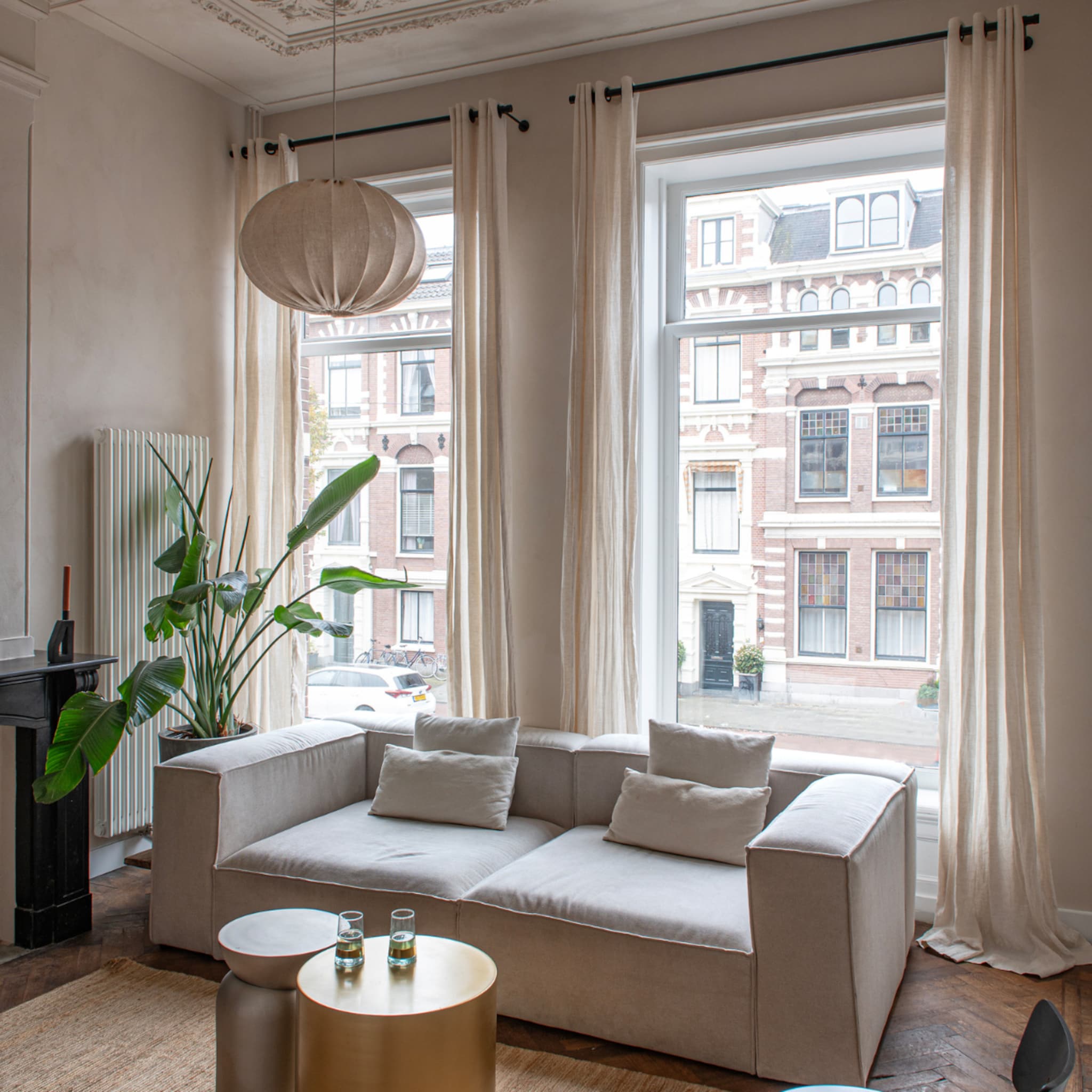 Woonkamer met grote ramen en creme kleurige plisse gordijnen