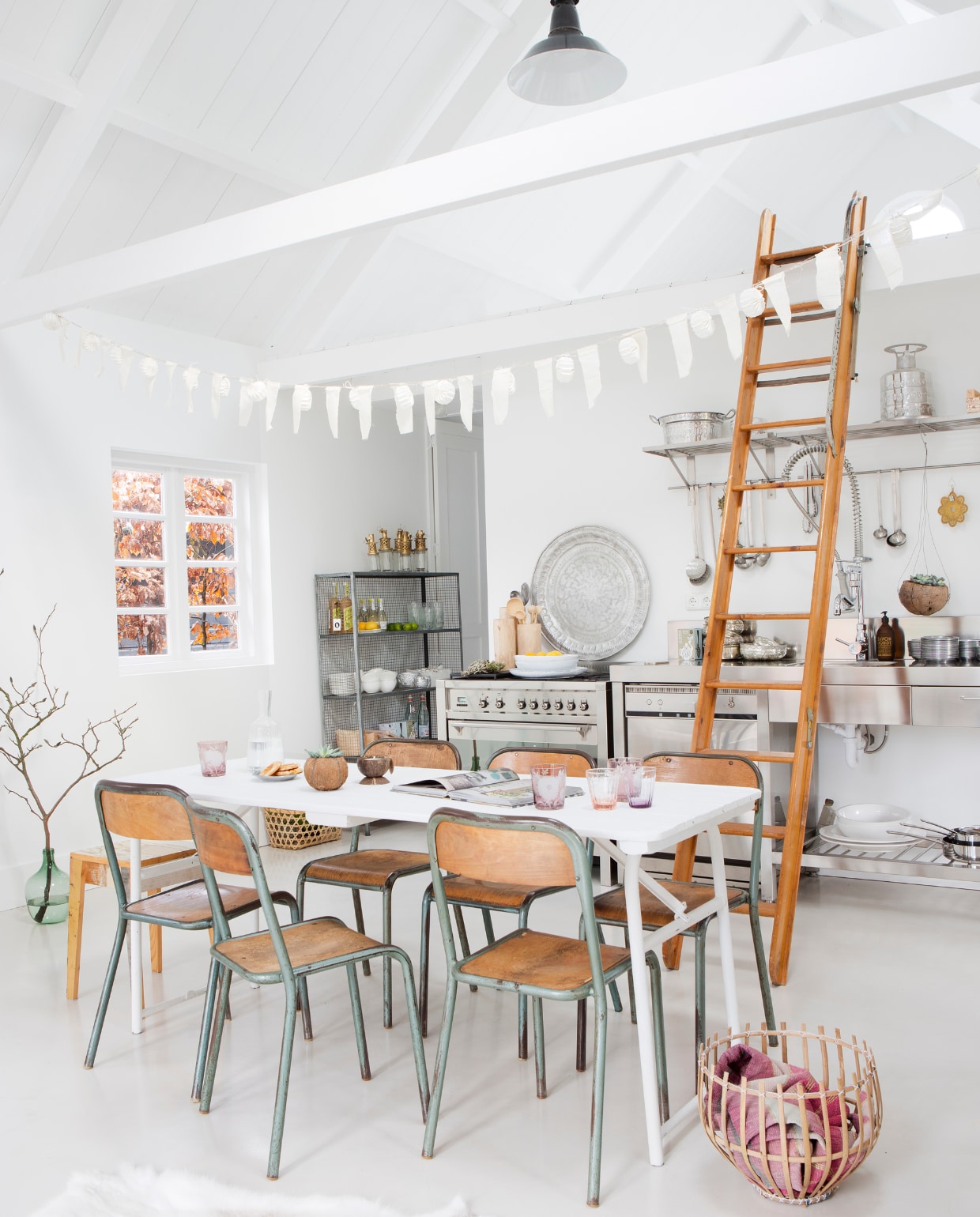Slinger van Sukha Amsterdam, lampionnensnoer van Nordal en hertenkop via L'etoile.store. De industriële lamp kocht ze bij Hal72, stoelen van Vivre Authentique, tafel van Combitex. Houten borden van HK Living. De glazen met bloemen zijn van Pols Potten. De andere glazen zijn van Bitossi, schaal van From Africa with Love, flesvaas en fotolijst van sloophout, alles via l’Etoile Conceptstore. Bank van Ikea. Kruk van Piet Hein Eek. Bamboe rolgordijnen van Leen Bakker. Op de vloer ligt beton van microcement.nl. vtwonen 12-2015 | fotografie Jeltje Janmaat | styling Elisabeth Borger