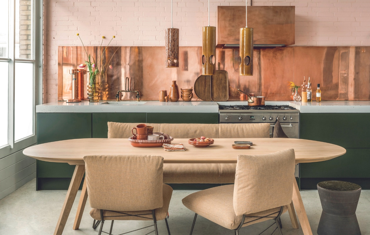 Koperplaat maatwerk, prijs op aanvraag (plaatopmaatwinkel.nl). Eikenhouten eettafel Mila Naturel Groove, 240x90x76 cm (bxdxh) € 1585,-, aardewerken bijzettafel Pawn van Serax, 40x38 cm (Øxh) € 349,- (loods5.nl). Eetkamerbank Cosy, metalen frame, 160x64x84 cm (bxdxh) € 1028,-, eetkamerstoelen Cosy, metalen frame, per stuk € 342,- (hetkabinet.nl). Keramieken hanglampen van HKliving in Lychee en Rosewood, per stuk € 149,-, keramieken schalen Mojave van HKliving, set van 2 € 17,99, gestreepte stoffen onderzetters van HKliving, set van 2 € 12,99 (vtwonen.nl/shop). Terracotta koffiekopjes met oor Barro, set van 2 € 29,-, terracotta ovenschaal met gestreepte rand Barro € 79,-, terracotta schalen Barro, set van 2 € 45,-(hay.nl). Roze stenen koffiemok met oor Jose € 17,50, terracotta koffiekopjes Juniper € 25,- (nordal.com). Op het aanrecht: bruiswatermachine Carbonator-3 in Copper € 210,- (aarke.nl). Bruine glazen vaas Maui € 37,95, terracotta kan Juniper € 30,-, terracotta karaf met dop Juniper € 75,-, terracotta schalen met handvatten Juniper, per stuk € 45,45, houten dienbladen Cajun € 45,- en € 50,- (nordal.com). Glazen tweedehands vaas rechts van het fornuis € 5,-(delokatie.org). Overig privébezit. vtwonen 05-2024 | styling Marianne Luning | fotografie Stan Koolen | assistentie Julia Beitler &amp; Rosa Neuteboom