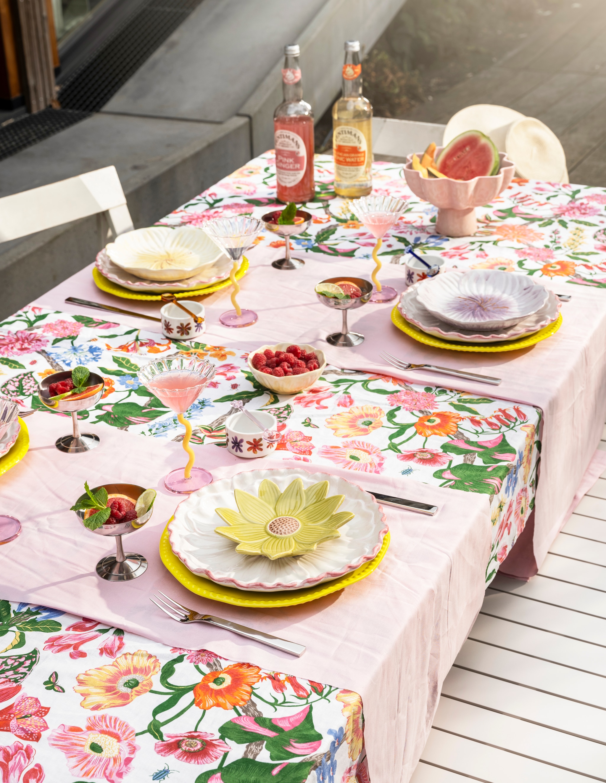 Gele porseleinen dinerborden Perle, set van 2 € 35,-, glazen lepels Daisy, set van 4 € 42,50, keramieken schaal op voet Sun € 49,- (klevering.com). Roze keramieken dinerborden Bloem € 7,99 (xenos.nl). Glazen coupes Curve van &amp;Klevering, set van 2 € 45,- (groenenakker.nl). Katoenen tafelkleed € 24,95 (hm.com). Wit gebloemd keramieken servies vanaf € 0,45 (dekringloper.nl). Rvs bestek Santiago van Alessi, 24-delig € 255,- (vtwonen.nl/shop). Rvs ijscoupes Italian € 19,- (hay.nl). Limonade Fentimans € 4,39 (ah.nl). Keramieken bloembord Savanna € 21,90, keramieken bloembord Mimosa, set van 2 € 54,90, keramieken schaaltje Mimosa € 14,99 (bloomingville.com). Houten klapstoelen van Aldo Jacober € 75,- (whoppah.com). Metalen tuintafel Vondel van Zuiver, 214x94x75 cm (bxdxh) € 1299,-, metalen tuinbank Vondel van Zuiver, 175x45x45 cm (bxdxh) € 749,- (vtwonen.nl/shop). Overig privébezit. vtwonen 06-2024 | styling Kelly van Gendt | fotografie Stan Koolen