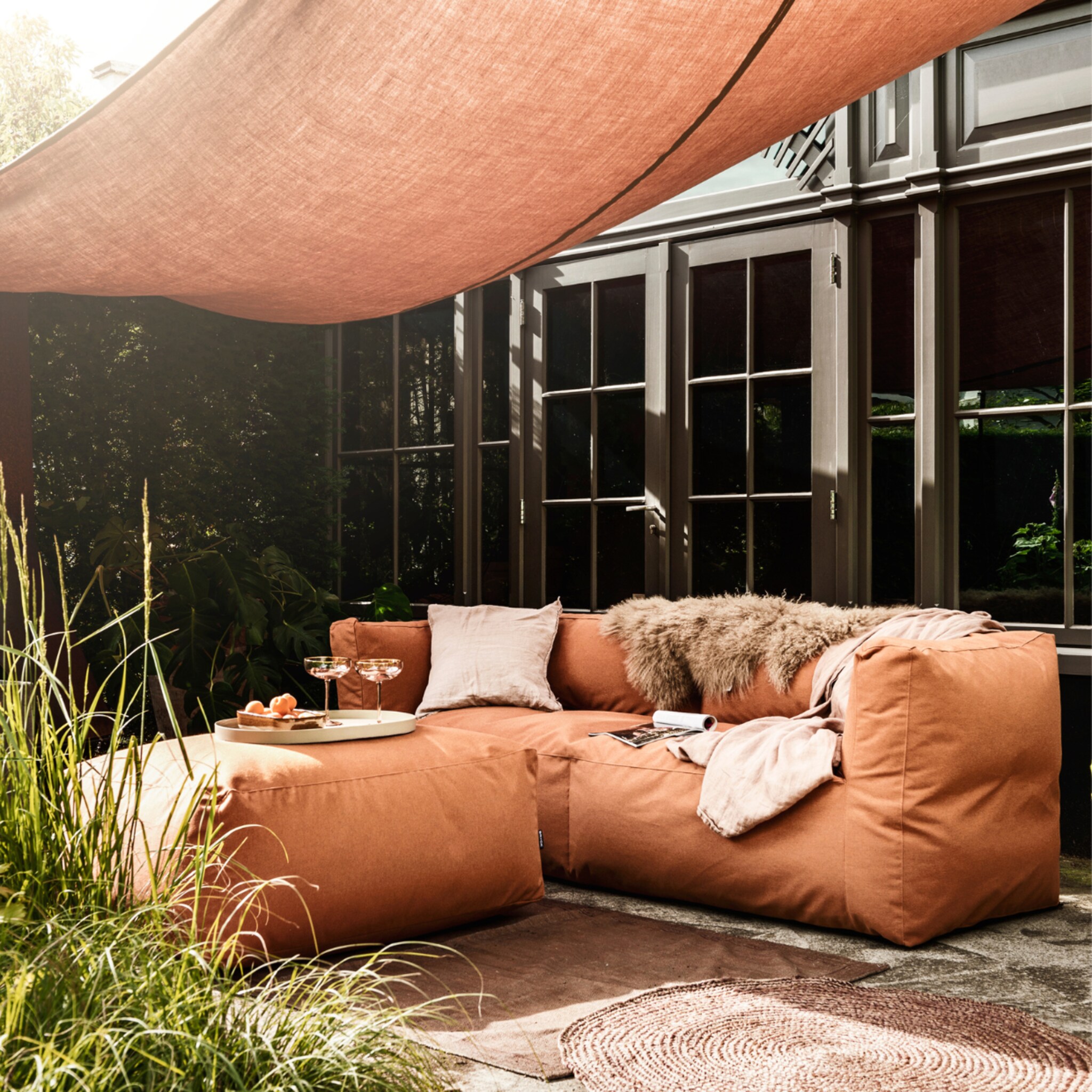 Tuin met terracotta kleur schaduwdoek en loungeset