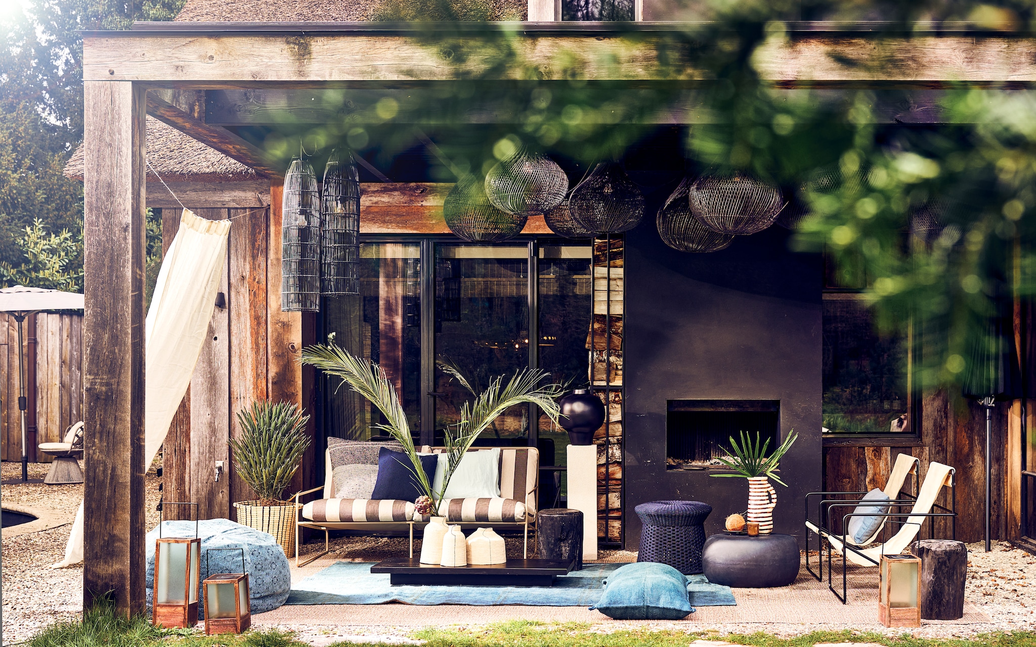 Stone washed poef Maison de Vacances links in beeld, katoen en viscose, € 695,-, terracotta gestreepte vaas Qayrawan, Unesco werelderfgoed € 189,-, lichtblauw linnen kussensloop Linge Particulier € 45,-, hennep tapijt, 273x180 cm € 1070,-, rieten plantenmand € 199,-, hennep kussen Kelim Graankussen #23 op de grond, 100x50 cm € 269,- (couleurlocale.eu). Fauteuils Desert van Ferm Living, metaal en gerecycled PET, 63x77,5x66 cm (lxbxh) per stuk € 355,-, tweezitsbank Desert van Ferm living, metaal en water-en-uv-bestendige outdoorstof € 2509,- (vtwonen.nl/shop). Rieten vazen op tafel van € 17,99 tot € 25,99, houten windlichten van € 49,98 tot € 89,99, linnen gordijn, 140x270 cm € 89,99 (zarahome.com). Gehaakte bijzettafel Dacks € 1312,-, denim kussen Tribù € 150,-, donkerblauw gehaakt kussen Tribù € 150,-, stoel met kussens links in beeld € 1756,- (dacks.nl). Sungkai-houten salontafel Plateau € 495,- (hkliving.nl). Keramieken mok € 7,99 (hm.com). Betonnen bijzettafel Pebble van vtwonen € 199,- (basiclabel.nl). Linnen kussensloop met patroon Francis € 118,- (libecohomestores.nl). Zwarte keramieken vaas Stor € 119,-, mangohouten zuil Pedestal Petrina, 80x20x20 cm (lxbxh) € 239,- (urbannatureculture.com). Planten en takken (plantje.nl). Schaaltje, Nederlands klei, prijs op aanvraag (sandravanriet.nl). Overig privébezit. vtwonen 2024-06 | Styling Liza Wassenaar | Fotografie Sjoerd Eickmans