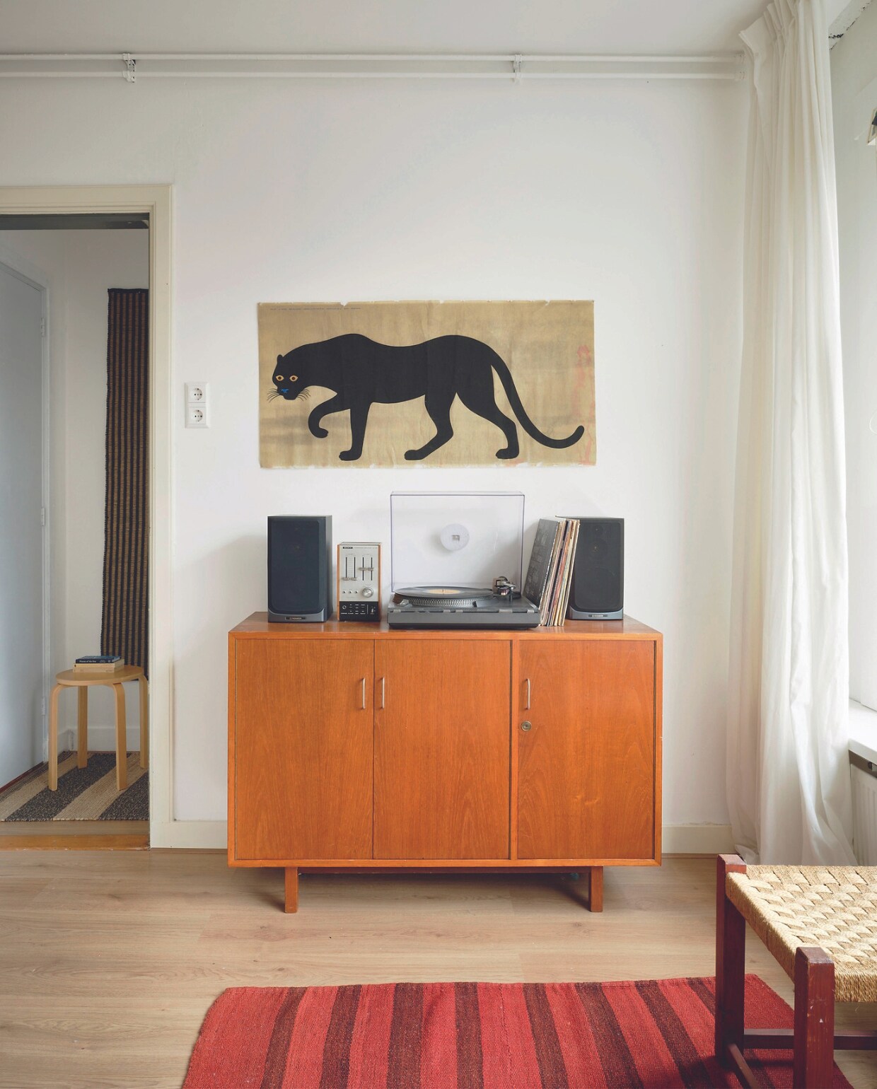 Kast, kelim en kruk vintage. Ronde kruk Alvar Aalto voor Artek, textielprint La Pantera van Enzo Mari, vintage platenspeler Technics en vintage versterker TA-88 van Sony. Overig onbekend. vtwonen 05-2024 | fotografie Mr. Frank