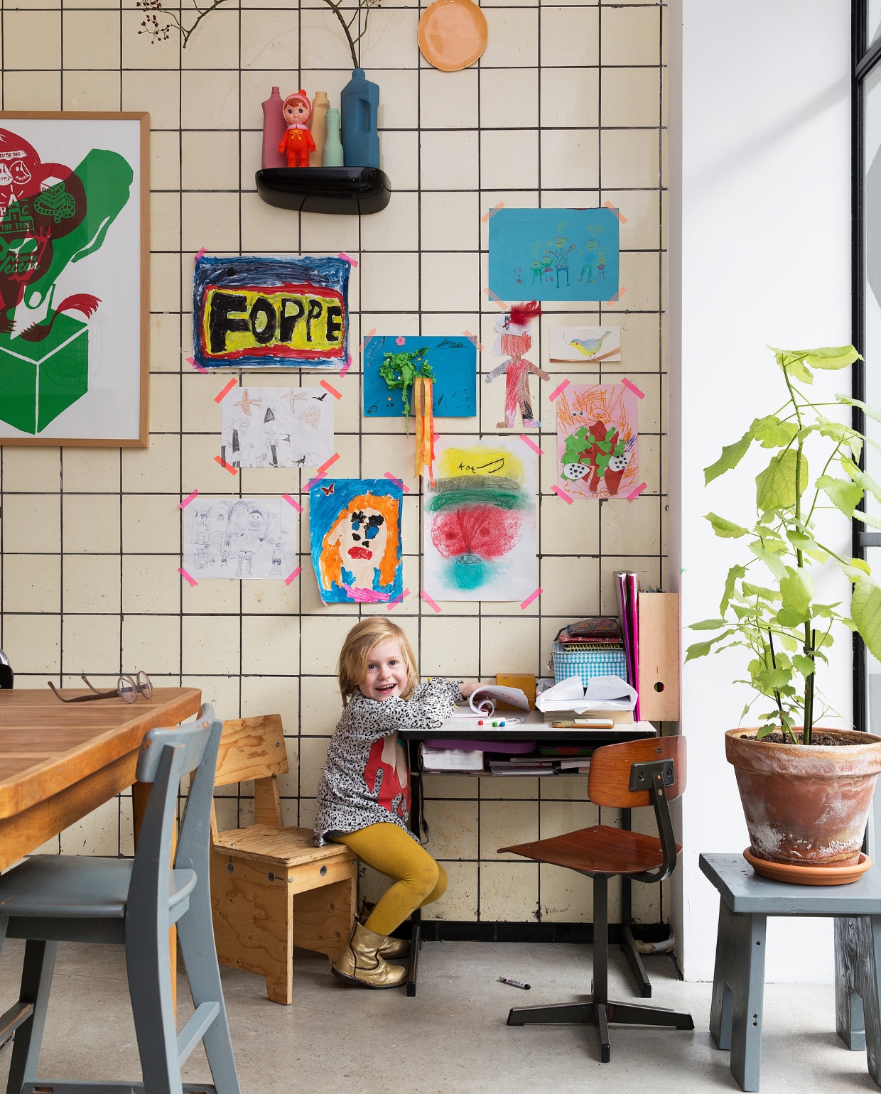 Aan de muur knutsels van de kinderen, bordjes van &amp;klevering, vazen van Foekje Fleur en een schilderij van Boxie1970. Lamp van Neef Louis. De grijze bank heeft Job, naar een voorbeeld in vtwonen, zelf gemaakt. Omdat er nog hout over was, maakte hij ook een bijpassend krukje. Houten kinderstoeltje is van Piet Hein Eek. Omdat buiten toevallig een beugel aan de muur hing, besloot het stel de oude racefiets van Job daaraan te hangen. En klaar was de geïmproviseerde – droge - opbergplek.Zwarte wandplank van Vitra, buitenbank van Leen Bakker. vtwonen binnenkijken special 121-2017 | styling Emmy van Dantzig | fotografie Jansje Klazinga