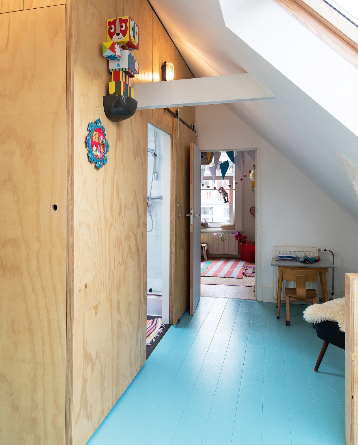 Zusje en Sientje hebben op hun eigen verdieping ook een eigen badkamertje.Voor de vloer werd de kleur blauw gekozen. Omdat er al zoveel hout gebruikt is, wil Jol kleur! ‘Dat blauw kwam zomaar bij me op. Roze op de vloer zou ik niet zo snel kiezen, dat vind ik dan weer te meisjesachtig. Onze werkwijze is als volgt: Job pakt de kleurenwaaier, we zien een mooie blauwe kleur, racen naar de winkel en gaan vervolgens meteen verven. Ach, we Ach we denken er niet te veel over na.’ Bureau en stoeltje van een rommelmarkt. vtwonen binnenkijken special 121-2017 | styling Emmy van Dantzig | fotografie Jansje Klazinga