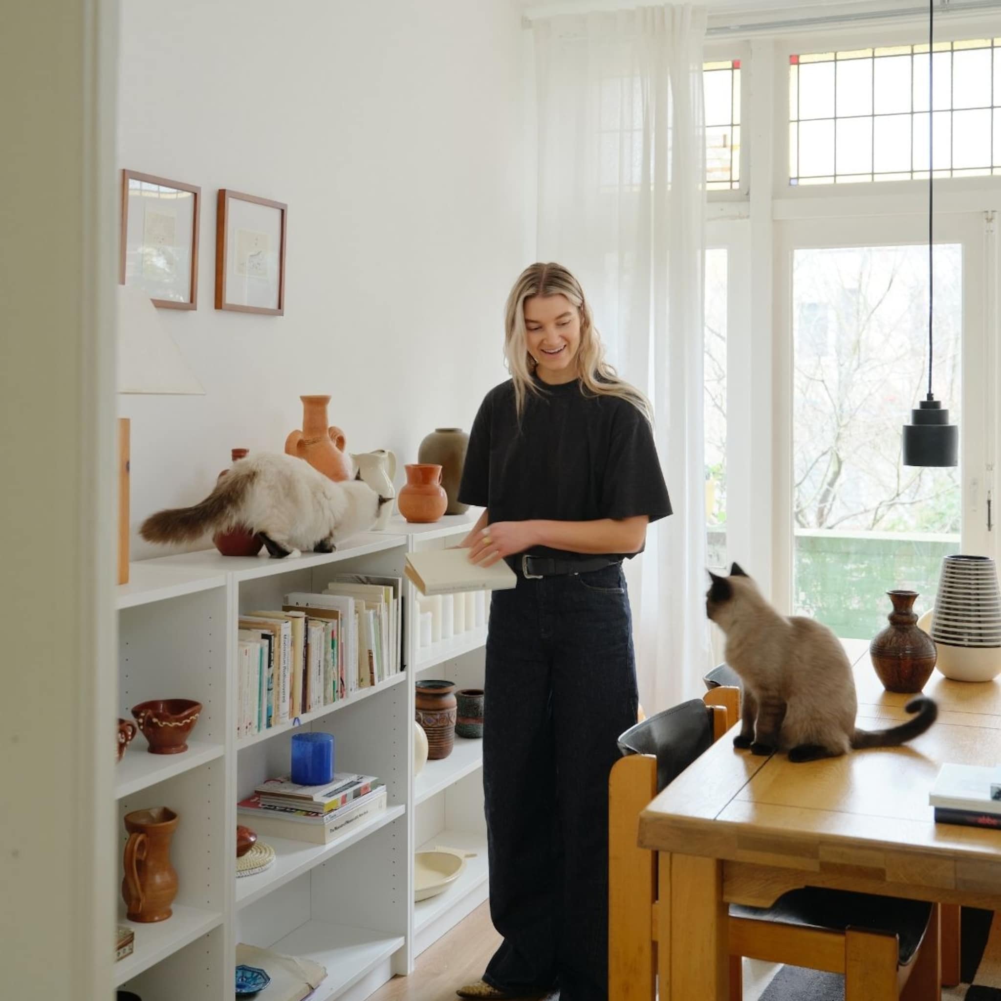 Houtentafel met eetstoelen en kast met vakken met twee katten