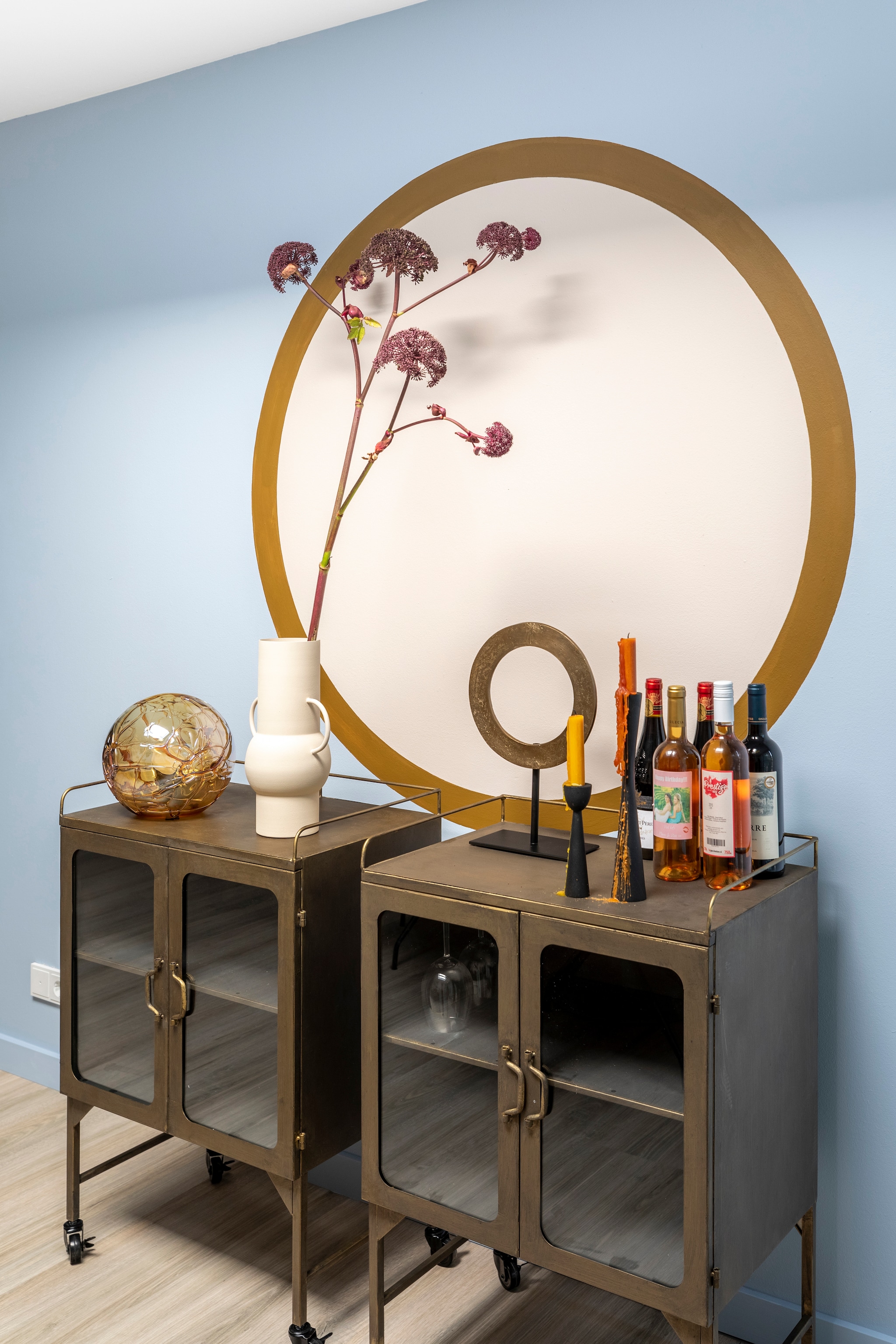 Linkermuur Flexa Creations muurverf ondergrond Bright Skies, cirkel Sandy Steps, rand Autumn Gold (flexa.nl). Vitrinekasten Talent van BePureHome, per stuk € 299,- (eijerkamp.nl). Ornament Walissa van Light &amp; Living € 30,95, vaas Jari van Mica Decorations € 49,95, zwartmetalen kandelaars van vtwonen vanaf € 15,20 (vtwonen.nl). Overig privébezit. Weer verliefd op je huis aflevering 4 seizoen 15 | styling Fietje Bruijn |  fotografie Margriet Hoekstra
