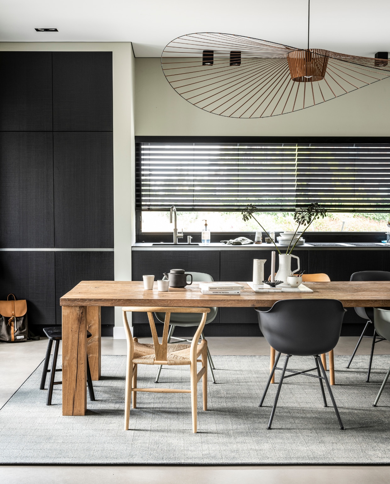 vtwonen collectie (Tapijt Herringbone Mud Grey, ook in Zinc, 400 cm breed, per strekkende meter € 169,95, vloerkleed op maat gemaakt prijsvoorbeeld 200x300 cm € 439,40) M.m.v. vtwonen.nl/vtwonen-collectie (plant en pot), vtwonen.nl (zwarte Eames vogel van Vitra), bepurehome.com (zwarte stoel, houten stoel, krukje), stories.com (vest), overig privébezit. vtwonen 22-2019 | productie Tanja Saarberg | styling Kim van Rossenberg | fotografie Sjoerd Eijckmans