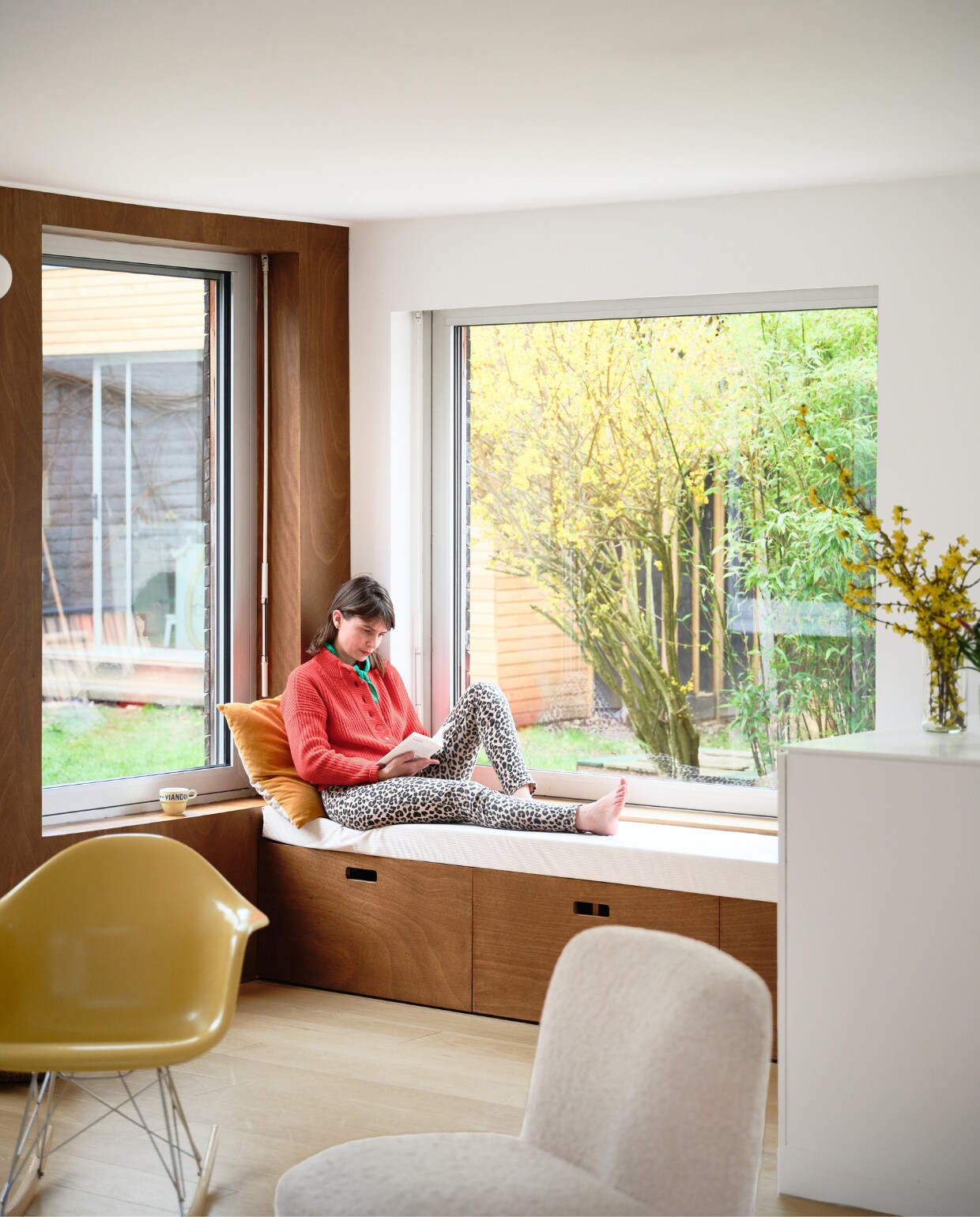 Schommelstoel Charles &amp; Ray Eames, witte stoel antiek, oranje kussen H&amp;M Home. Witte kast en bank voor het raam zelfgemaakt door Mathieu. vtwonen binnenkijken special 131-2024 | productie Living Inside | fotografie Mr. Frank