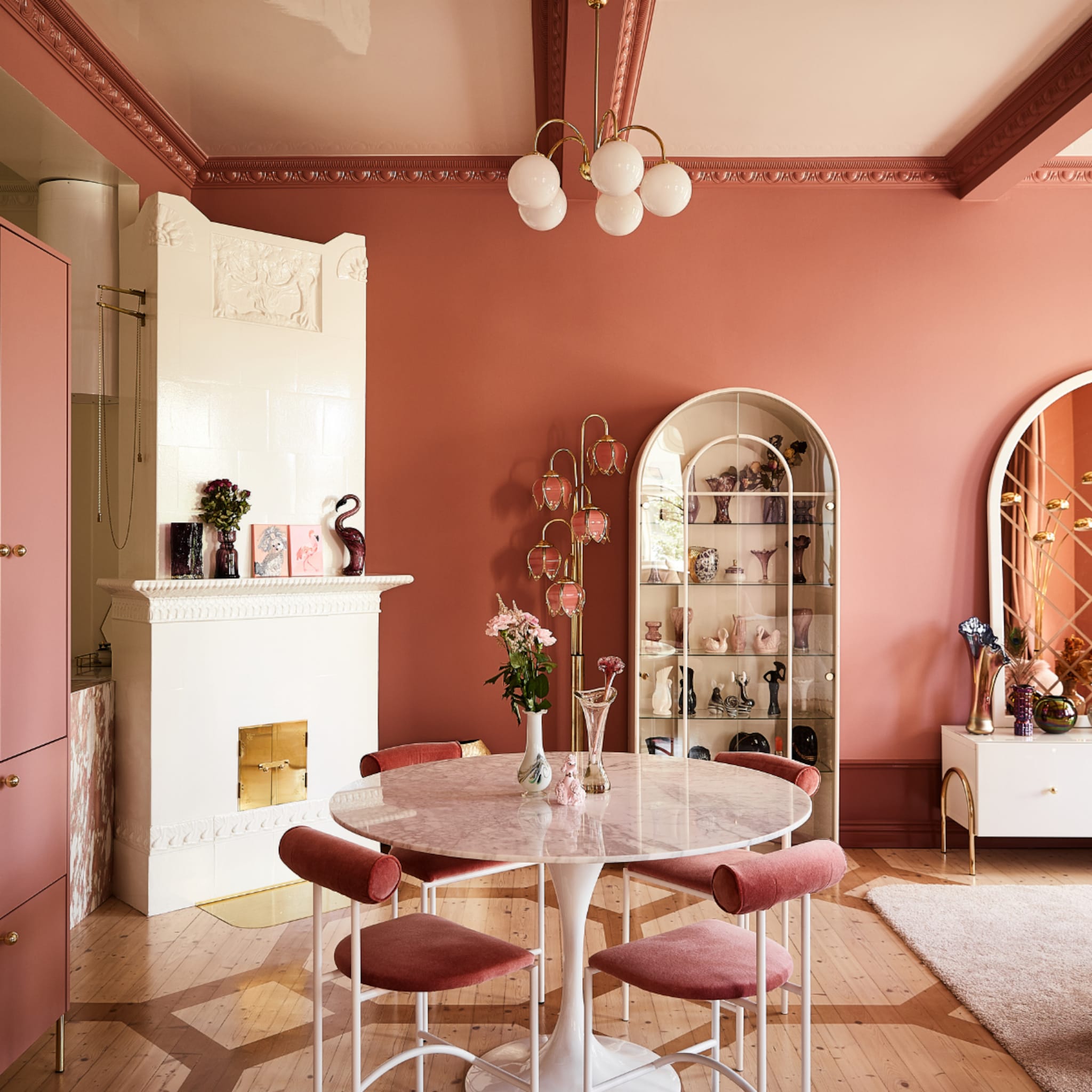 Roze woonkamer met witte ronde eettafel en roze stoelen
