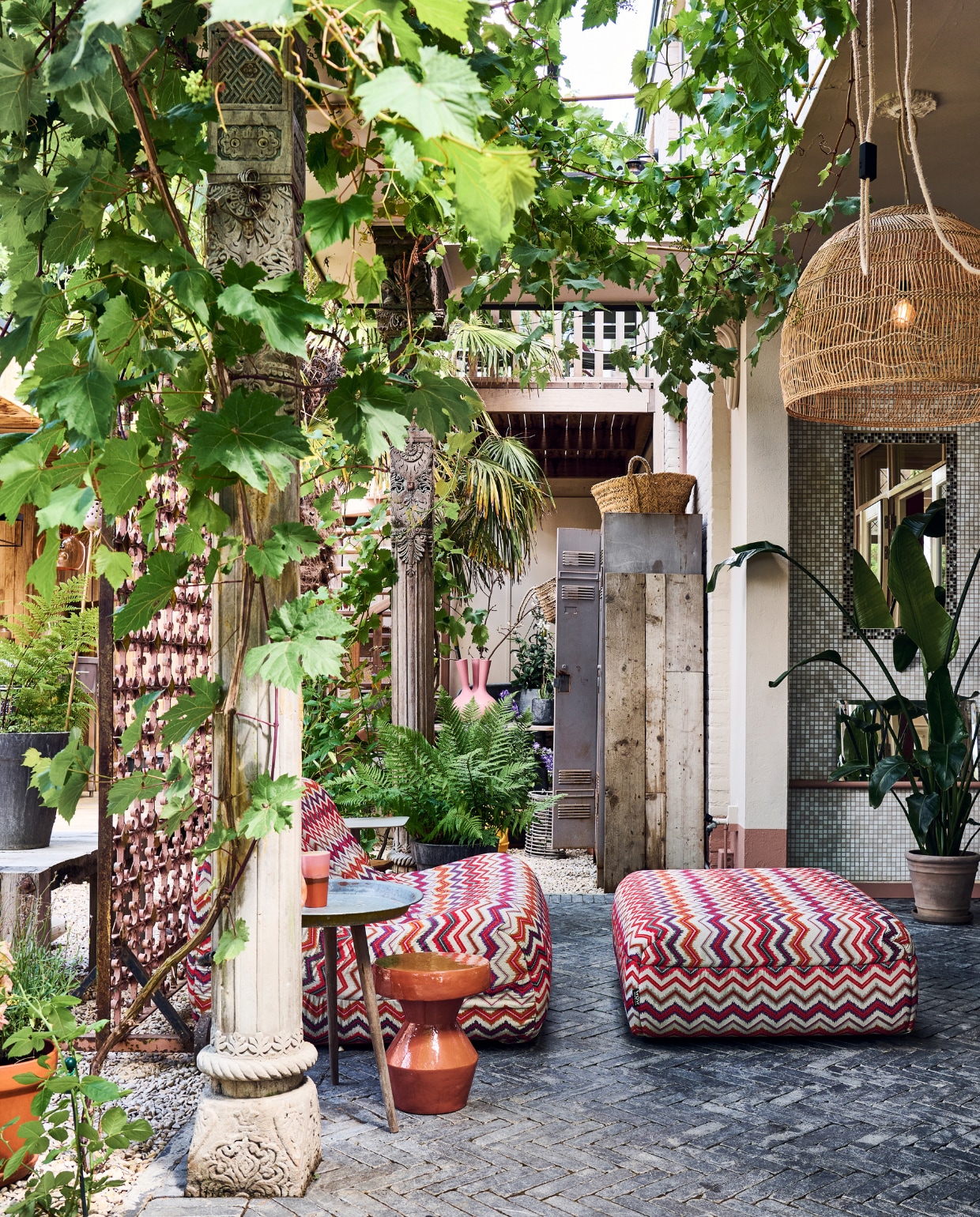 De veranda bij het huis is net een Marokkaanse binnenplaats. Ertegenaan klimmen een druif en klimroos. De pilaren stonden er al. Outdoor loungebank met hocker Muna met stof Fiesta van evavandeven.nl. Keramieken bijzettafel Urban Nature Culture, bijzettafel op poten Kwantum, witte bijzettafel Karwei. Kandelaar en mand Household Hardware. Hanglamp en mok HKliving. vtwonen special tuin 10 | styling Liza wassenaar | fotografie Sjoerd Eickmans