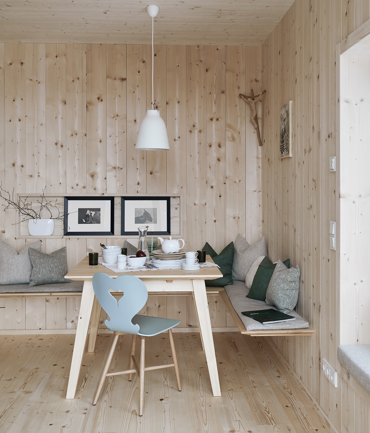 Vurenhouten wandbekleding en vloer. Tafel op maat gemaakt door een lokale timmerman, stoel Trix van Schmidinger Möbelbau. Linnen kussens van Leitner Leinen, wollen kussens van Loden Steiner. Servies Piana van Lambert, hanglamp Caravaggio van Fritz Hansen, ingelijste prints uit een kalender. Herkomst overige items onbekend vtwonen 13-2020 | productie Features &amp; More | styling Wilma Custers | fotografie Krista Keltanen