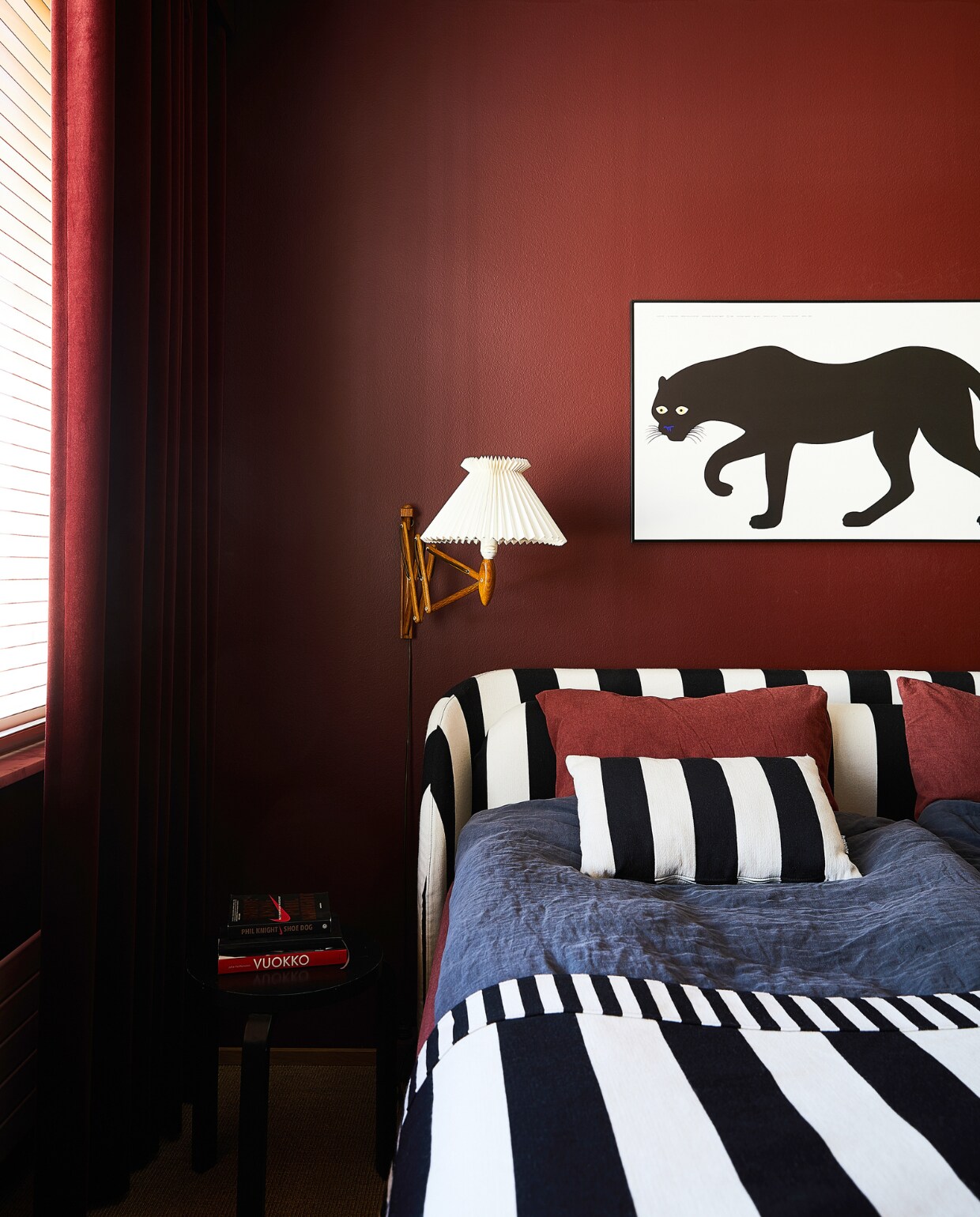 Bordeauxrode verf Oscar van Cover Story Paint-selectie, bed Hakola gestoffeerd met zwart-witte strepen, zwart-witte wollen deken Hakola, wandlampen Saxit van Le Klint, panterschilderij uit Annaleena’s vorige huis. vtwonen binnenkijken special 131-2024 | productie Living Inside | styling en tekst Jonna Kivilahti | fotografie Krista Keltanen
