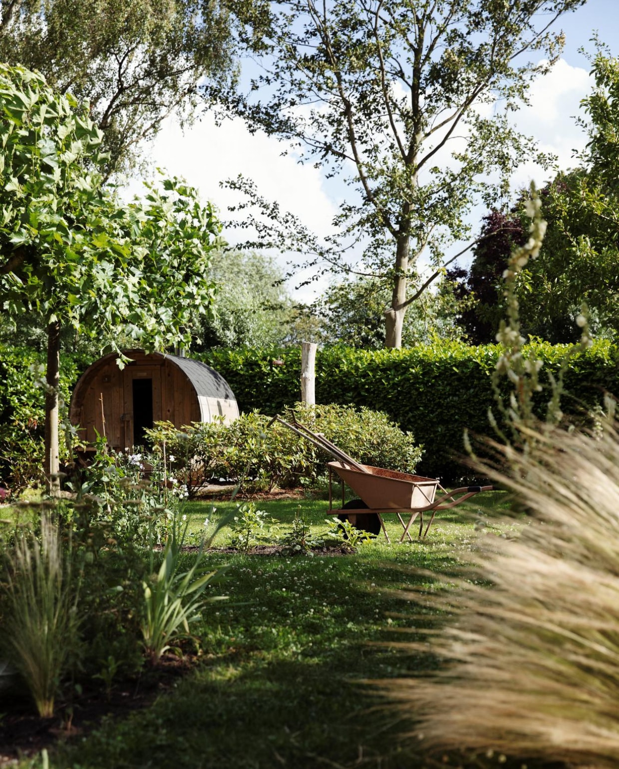 Sauna van Barrelsauna. Taxus- en laurierhagen en een wand van bamboe vormen de erfafscheiding, alles blijft groen in de winter. In de border bij de sauna staan rododendrons. vtwonen Tuin 10 | styling Ilona