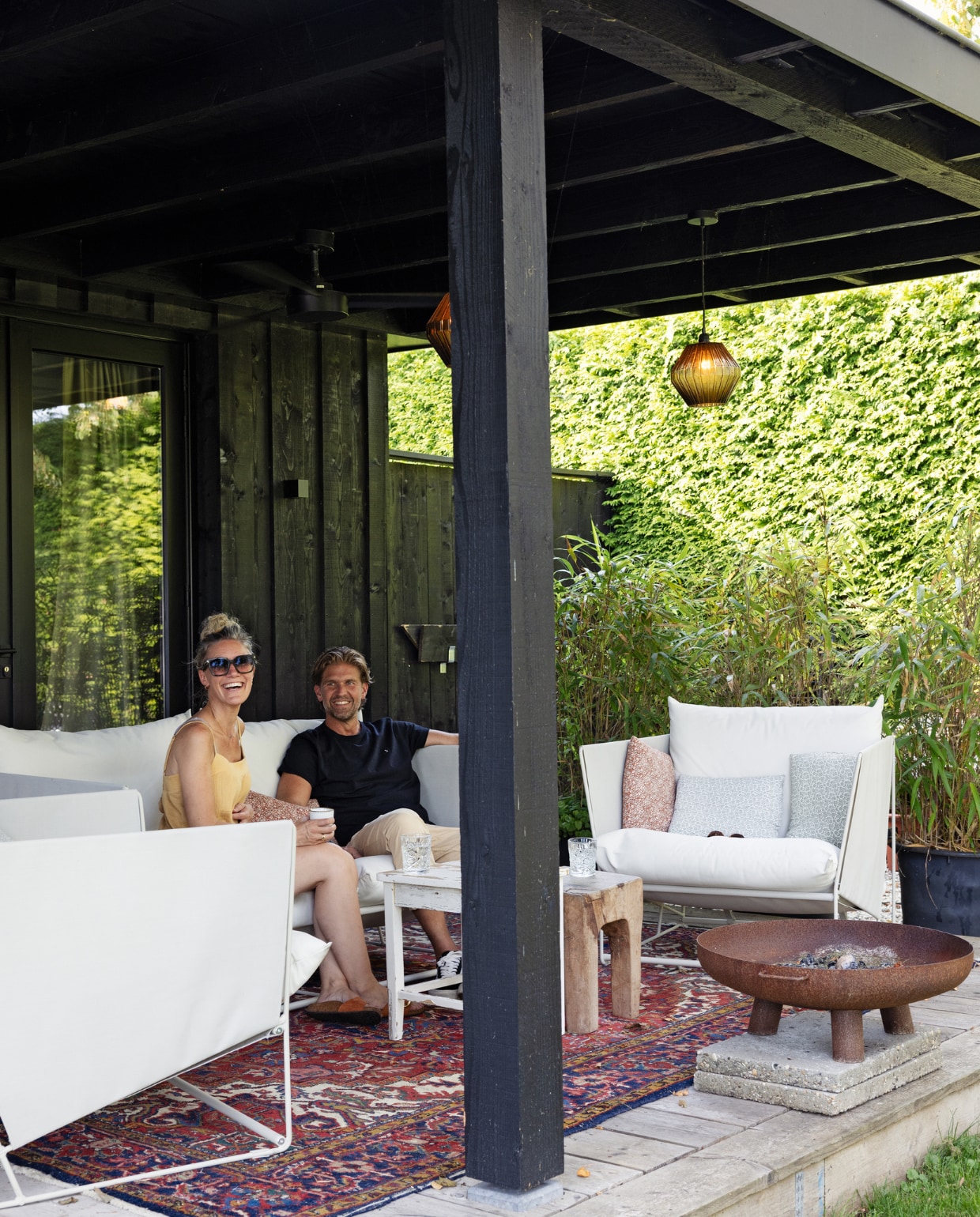 In de bakken staat bamboe, daarachter coniferen. Tuinmeubels Ikea, Perzisch kleed Hype Popup, kussens Xenos, vuurschaal Intratuin, houten tafel Loods 5, lampionlampen Monday Sunday. vtwonen Tuin 10 | styling Ilona Jongepier | fotografie Dana van Leeuwen