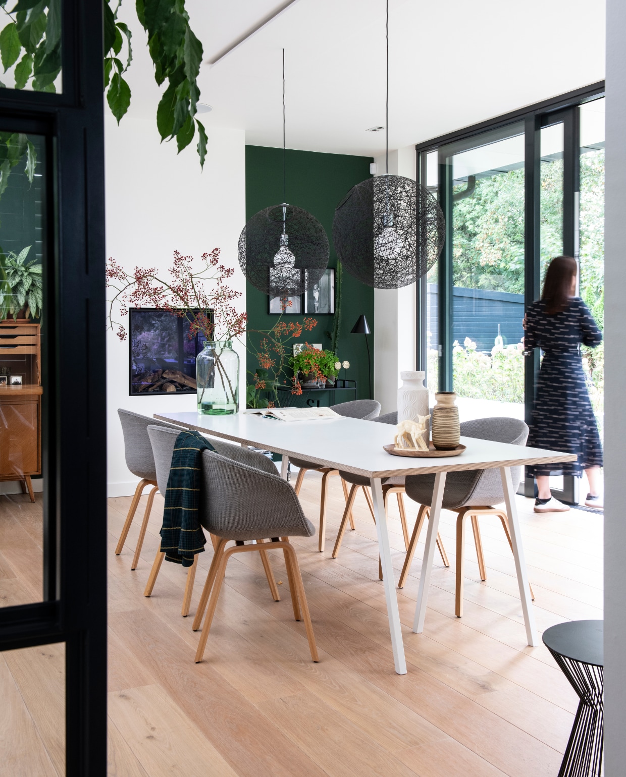 De tuinkamer met ‘de stamtafel’ van Hay. Eikenhouten vloer van Dirkedaen. Stoelen Hay, zwarte hanglampen Moooi. Vintage vazen, gekocht in diverse curiosa winkels. Hertjes vintage design uit de jaren 70. Vintage vaas van West Germany. Zwarte trolley en vloerlamp House Doctor. Groene verf van Histor. Illustratie van Geertje Aalders. vtwonen 05-2019 | styling Inge van Lieshout, Inside Homepage | fotografie Louis Lemaire, Inside Homepage