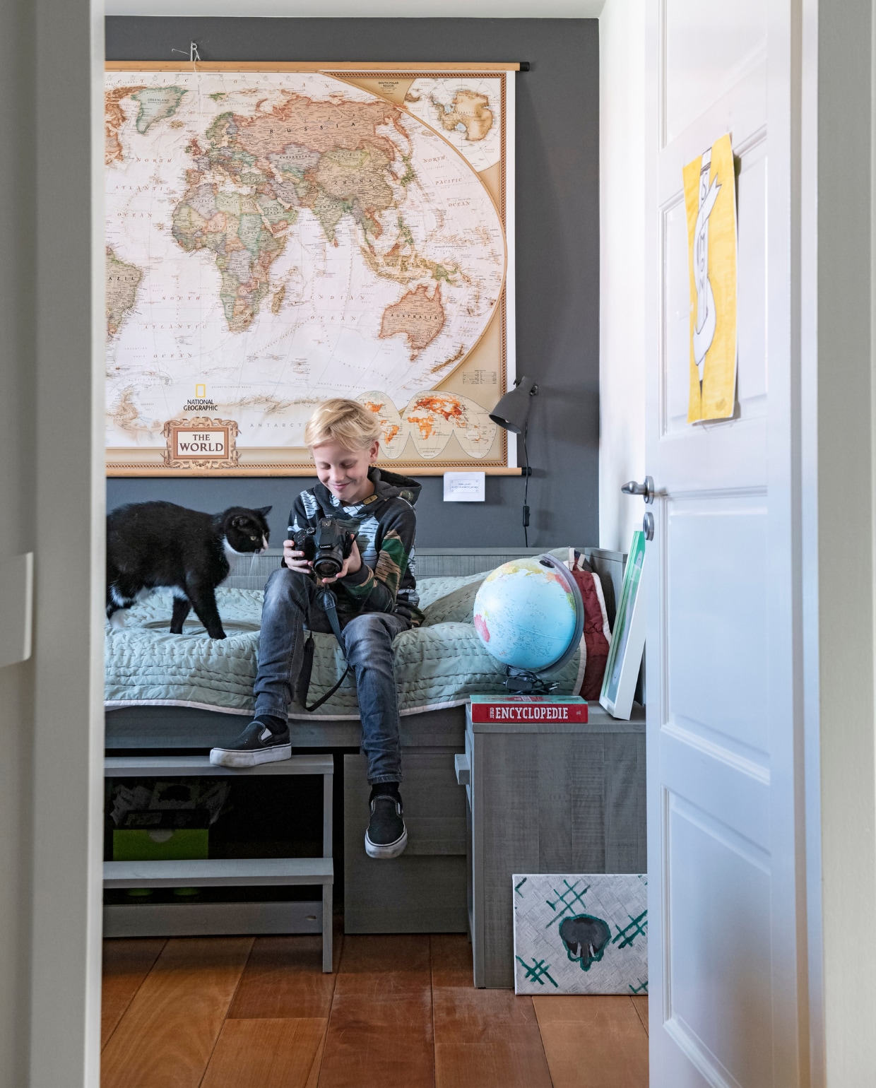 Simon met kat Moos op zijn kamer. Bed van Coming Kids, sprei van Hay, wereldkaart National Geographic, wereldbol bol.com. vtwonen 05-2019 | styling Inge van Lieshout, Inside Homepage | fotografie Louis Lemaire, Inside Homepage