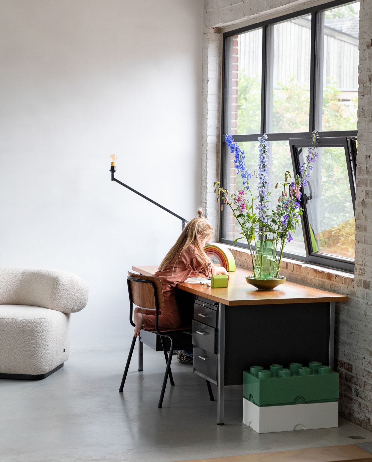 Bureau en bureaustoel erfstukken. Fauteuil Luna Lounge Chair Studio Henk. Speelgoedbakken Lego. Vaas Elleke Rutten. Houten regenboog Grimm. Kozijn aluminium steellook profiel, 50 mm Aliplast. vtwonen 01-2022 | styling Ilona Jongepier | fotografie Dana van Leeuwen | visagie Djolien de Kreij