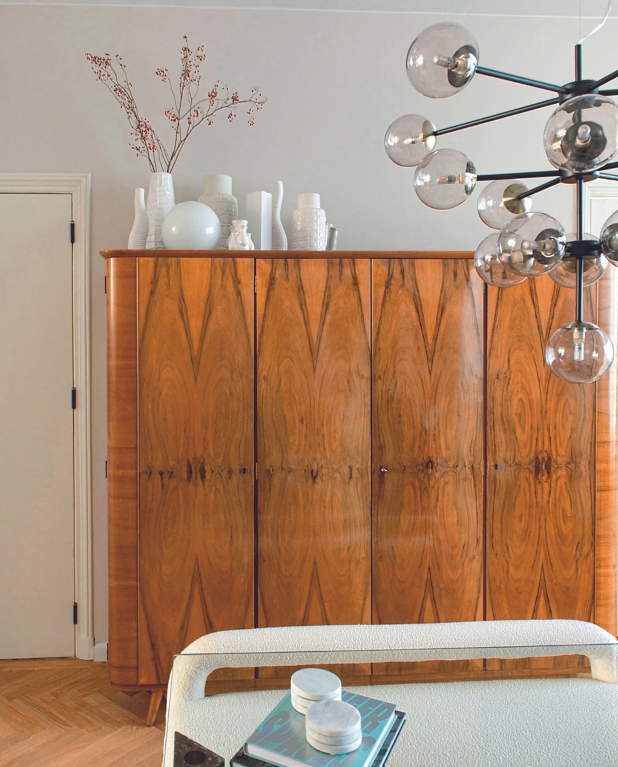Handgemaakte kledingkast uit 1957 Marktplaats. Verzameling witte vazen Marktplaats en kringloopwinkel. Bolvormige tafellamp Ikea. Hanglamp en bank Made. Overig onbekend. vtwonen 05-2024 | productie De Binnenkijkers | styling Jeske Weel | fotografie Caroline Coehorst