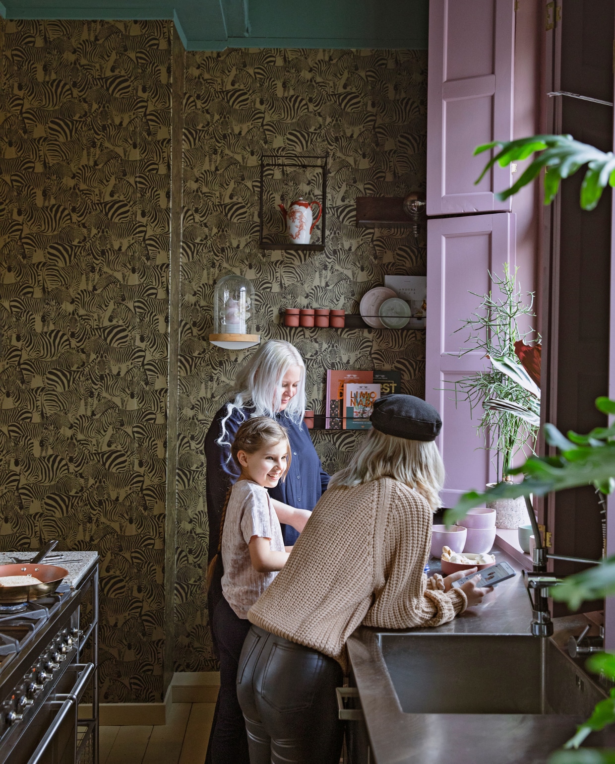 Behang Zebra’s in goud van Origin wallcoverings. Verfkleur luiken Velvet Plum en plafond Peacock van Painting The Past. Keuken Ikea met op maat gemaakt aanrechtblad. Koperen pan Ikea. Wandstolp Nørd conceptstore met daarin theekopjes van de Bijenkorf. Metalen wandrekjes Ikea en Stoer Metaal. Porseleinen theepot tweedehands. Keramieken mokjes in terracotta Archive Studio. Sierborden Studio Harm en Elke. Roze kommen op aanrecht Lydia Elisabeth Pottery. vtwonen 06-2021 | styling Ilona Jongepier | fotografie Dana van Leeuwen
